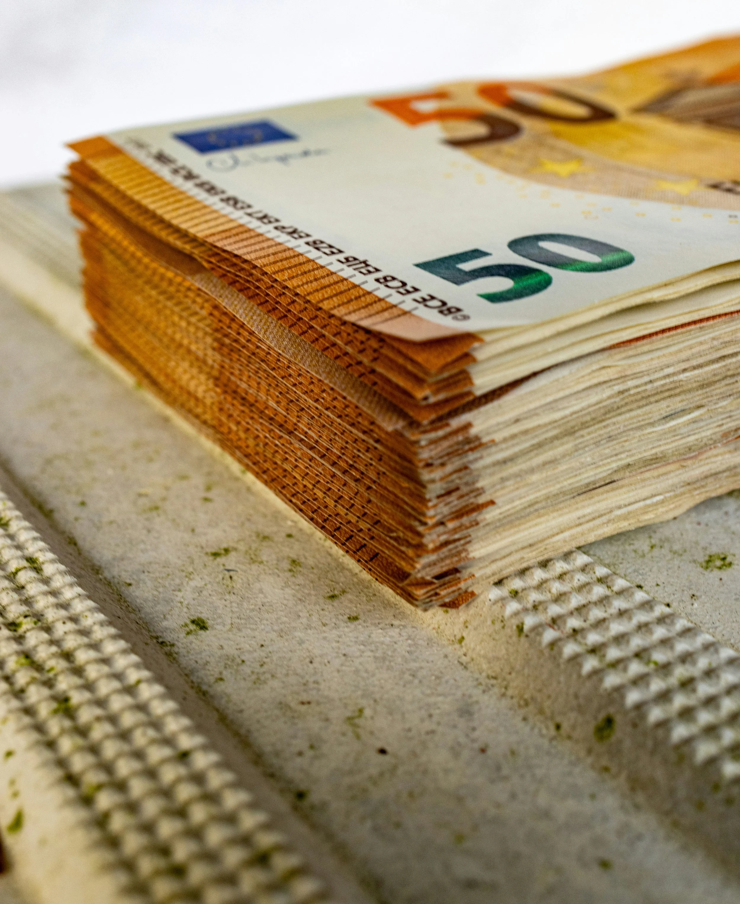 Stampa di banconote da cinquanta euro, sovrapposte e disposte su una superficie.