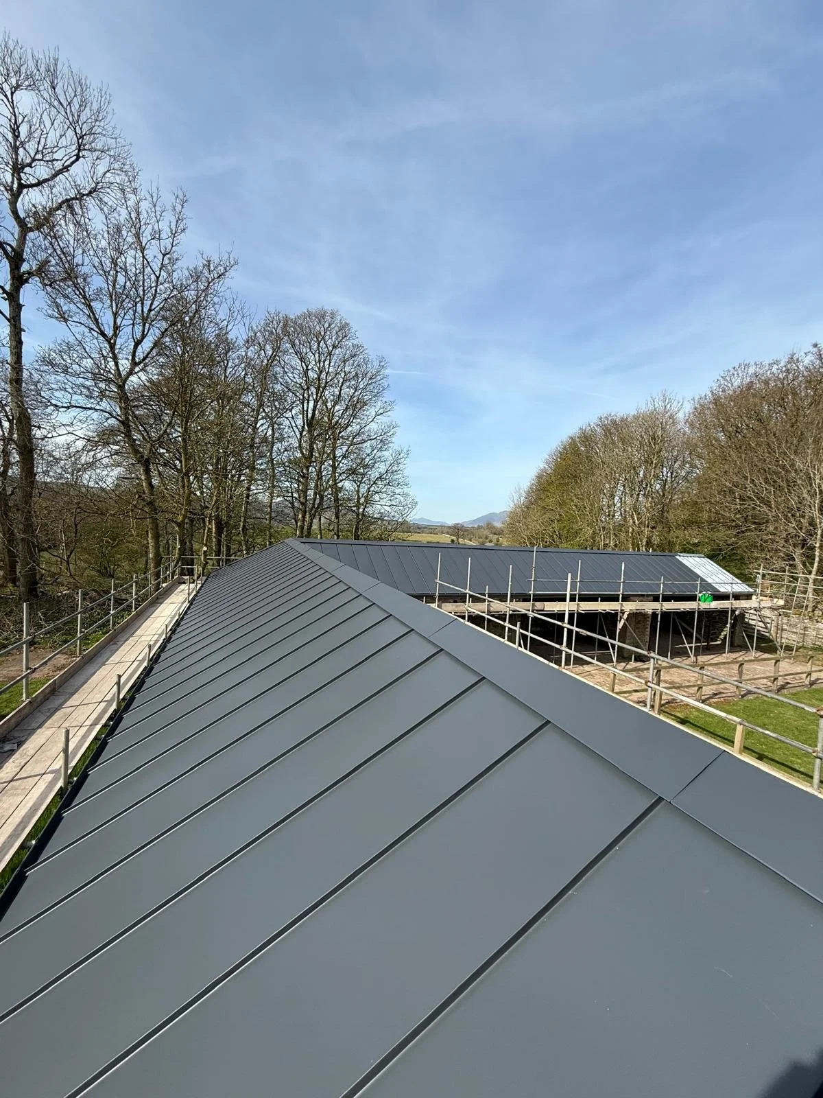 Immaculate dark grey standing seam metal roof installation on a rural residential property refurbishment in Cumbria, showcasing precise structural detailing by ELAST.