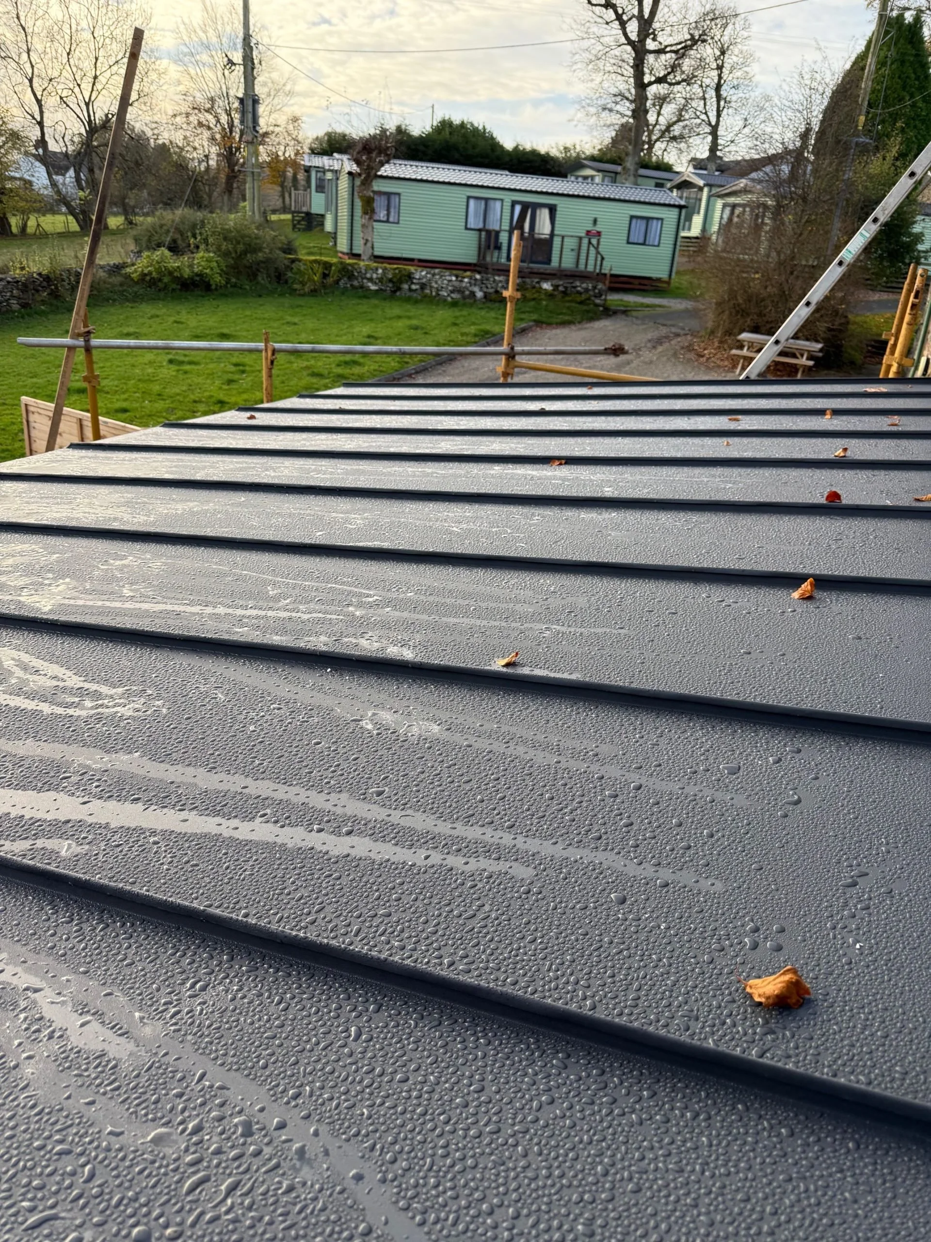 Close-up of the textured, slip-resistant finish on high-performance standing seam sheets during an early morning installation.