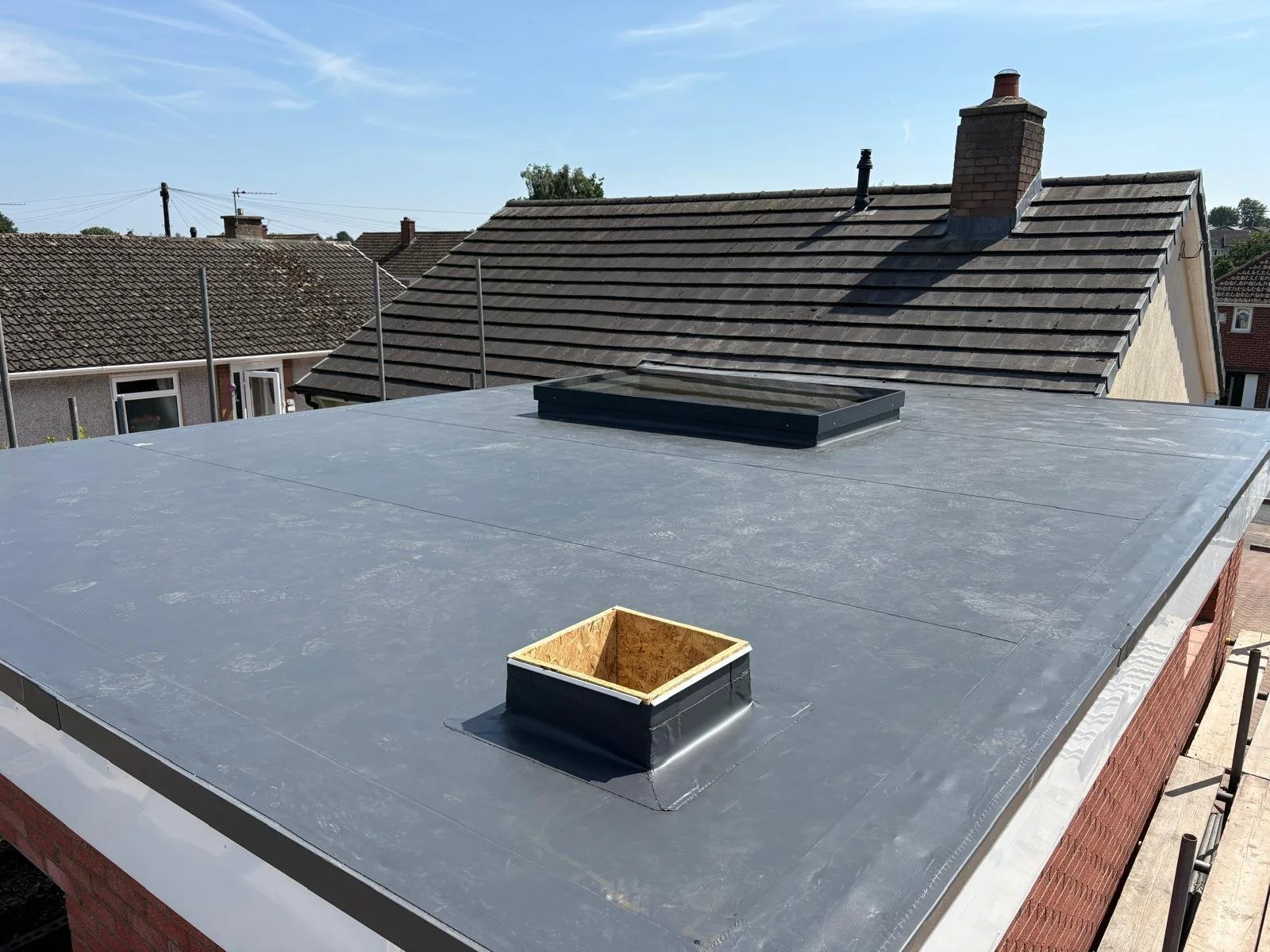 Modern flat roof installation on a residential home extension in Cumbria featuring a central glass skylight lantern.