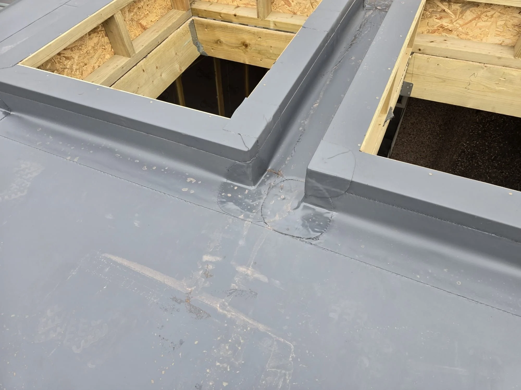 Technical view of grey membrane welding around timber roof lantern frames during an extension build in Cumbria.