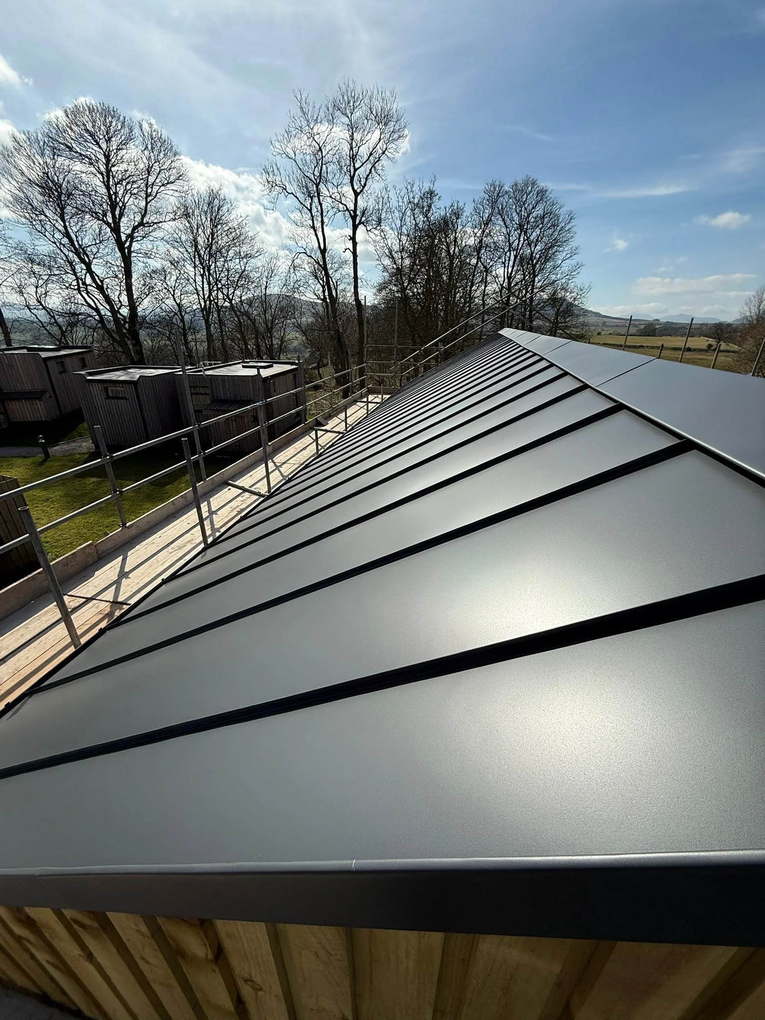 Mid-range detailed shot from the access walkway, highlighting the flawless alignment, perfectly straight parallel seams, and crisp panel joinery on a bespoke residential standing seam roof installation.