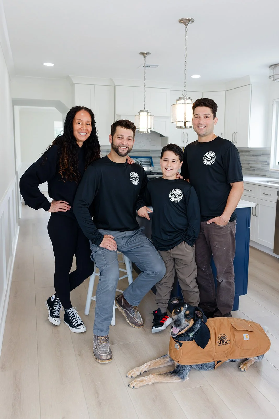 A family of four with a service dog in a modern kitchen, all smiling at the camera.