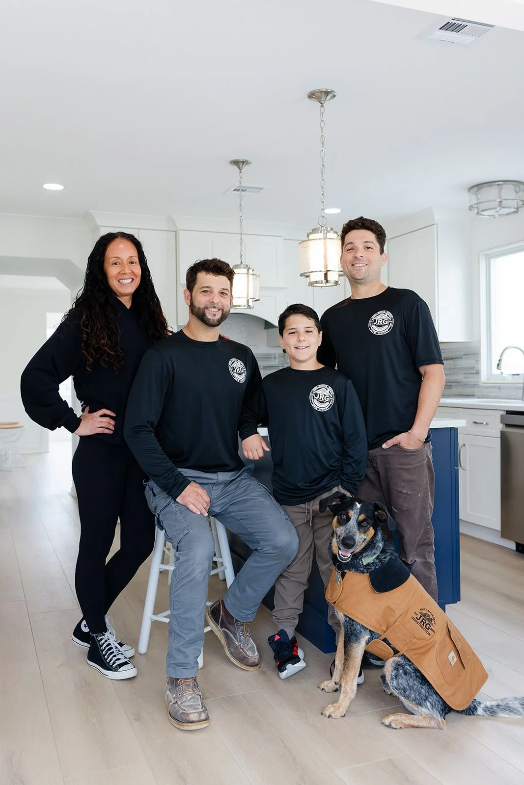 Family of four with a service dog, standing in a white modern kitchen.