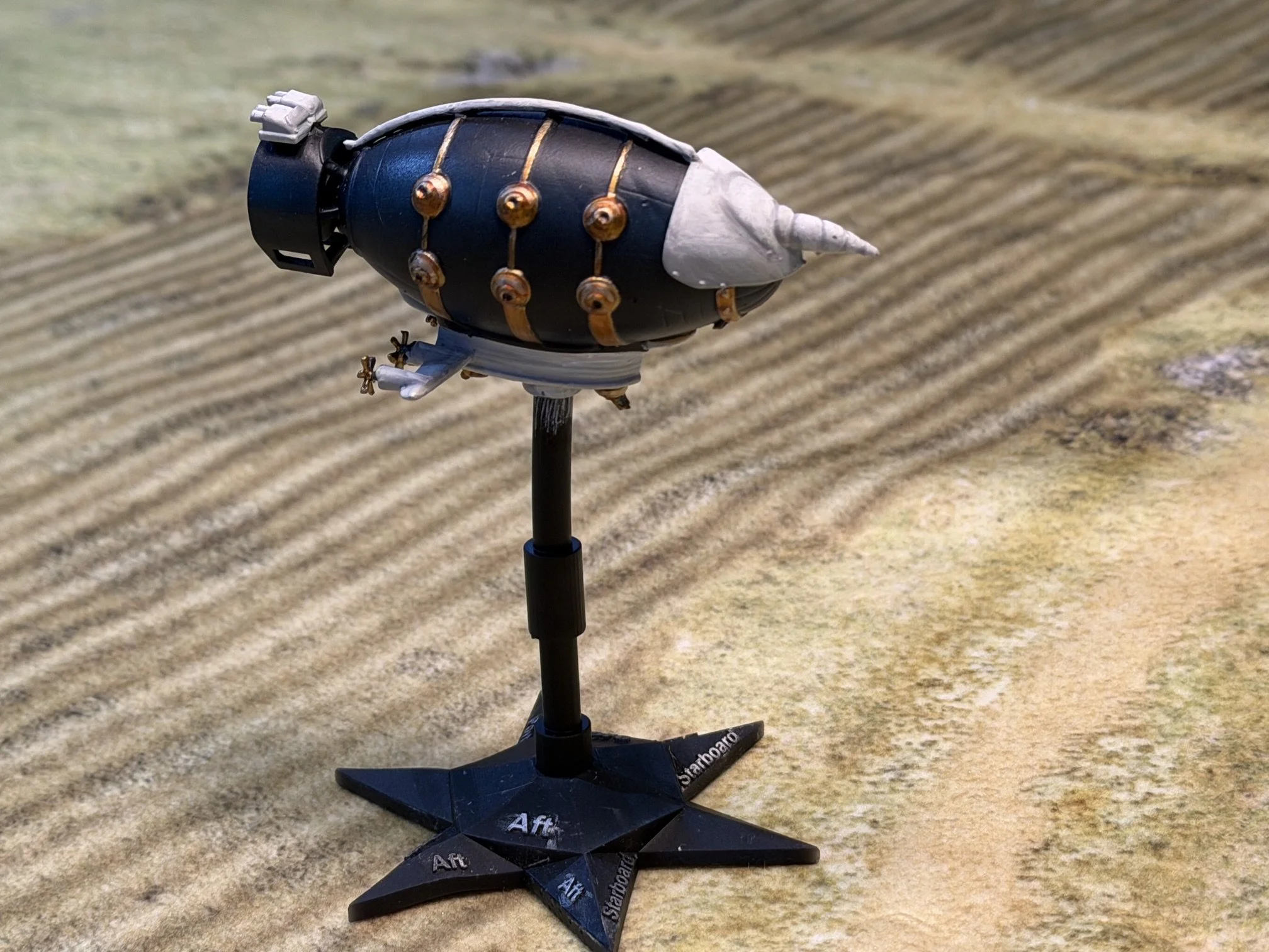 A model of a missile or rocket mounted on a stand on a textured surface with parallel lines.