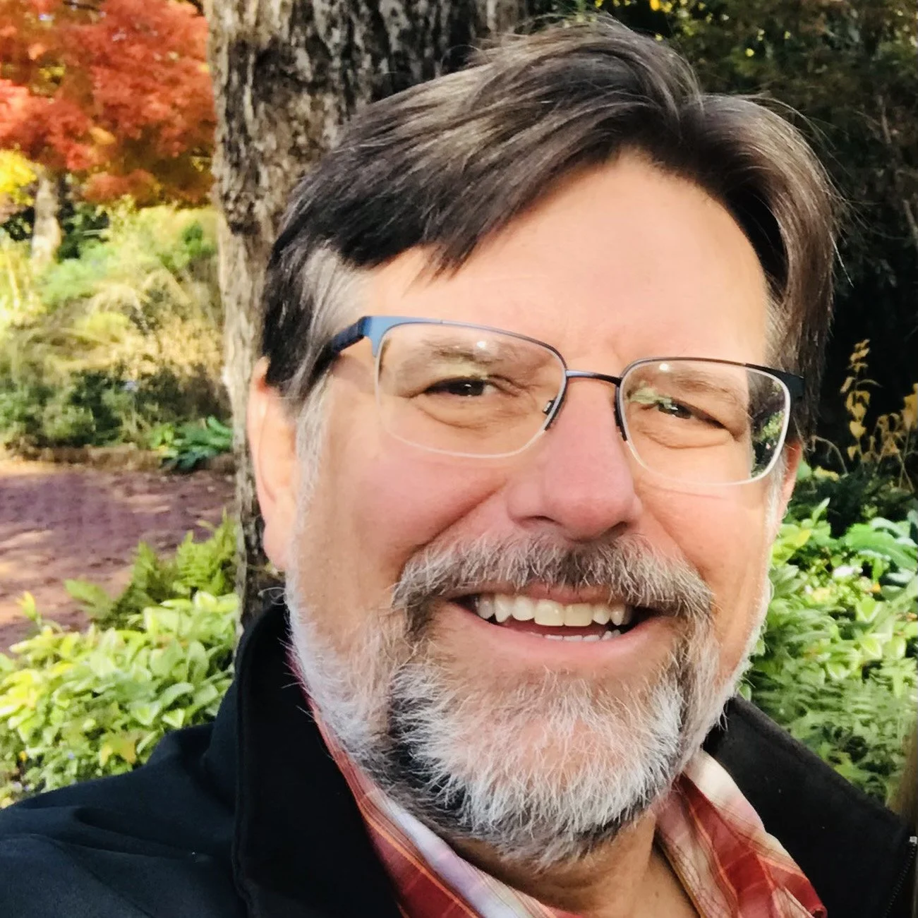 Headshot of smiling male tutor with short locks wearing a lanyard.