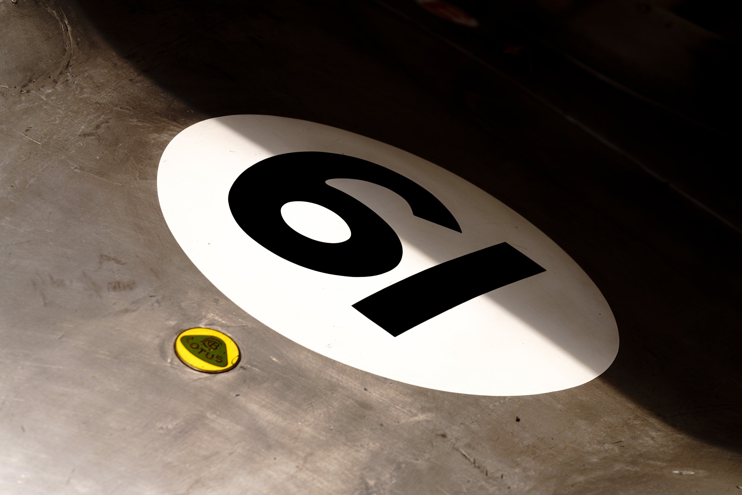 Close-up of a racing number 19 on dark bodywork at Donington Historic Festival.