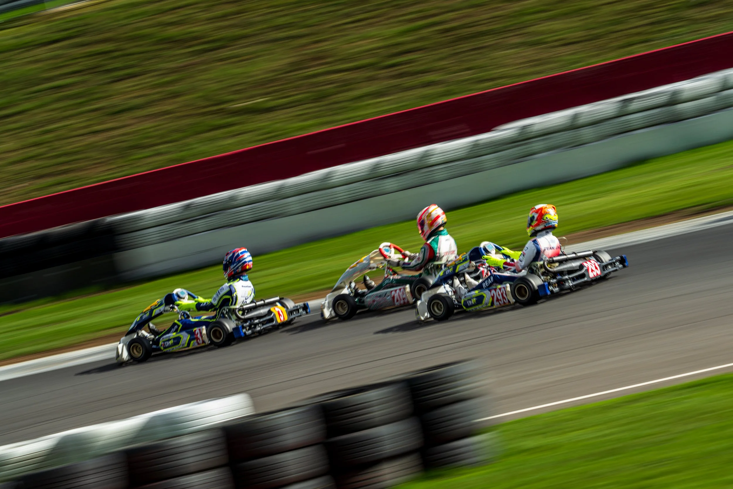 A group of kart racers competing closely together at Silverstone.