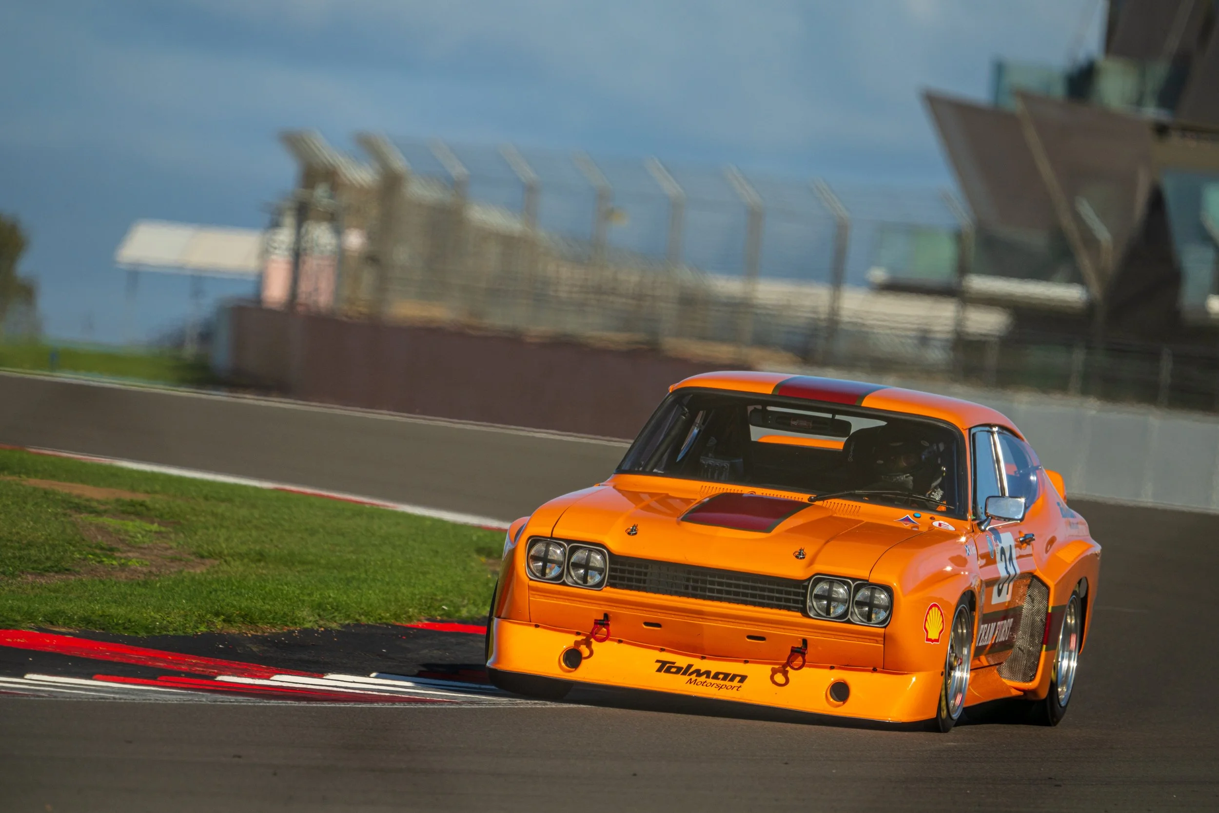 Orange touring car taking a corner on the Silverstone Grand Prix circuit.