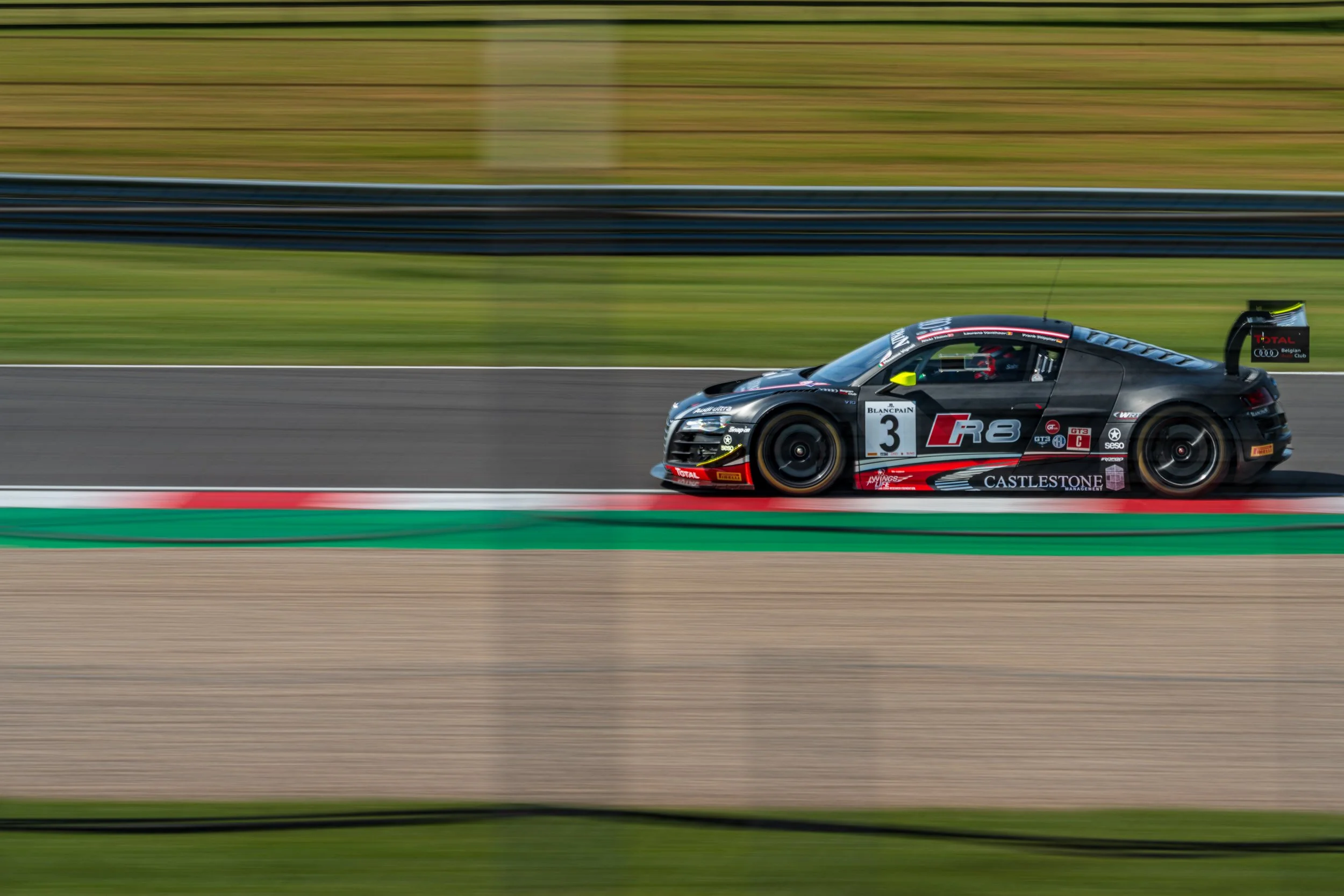 Black GT racing car captured in a side-on panning shot at Donington Park.