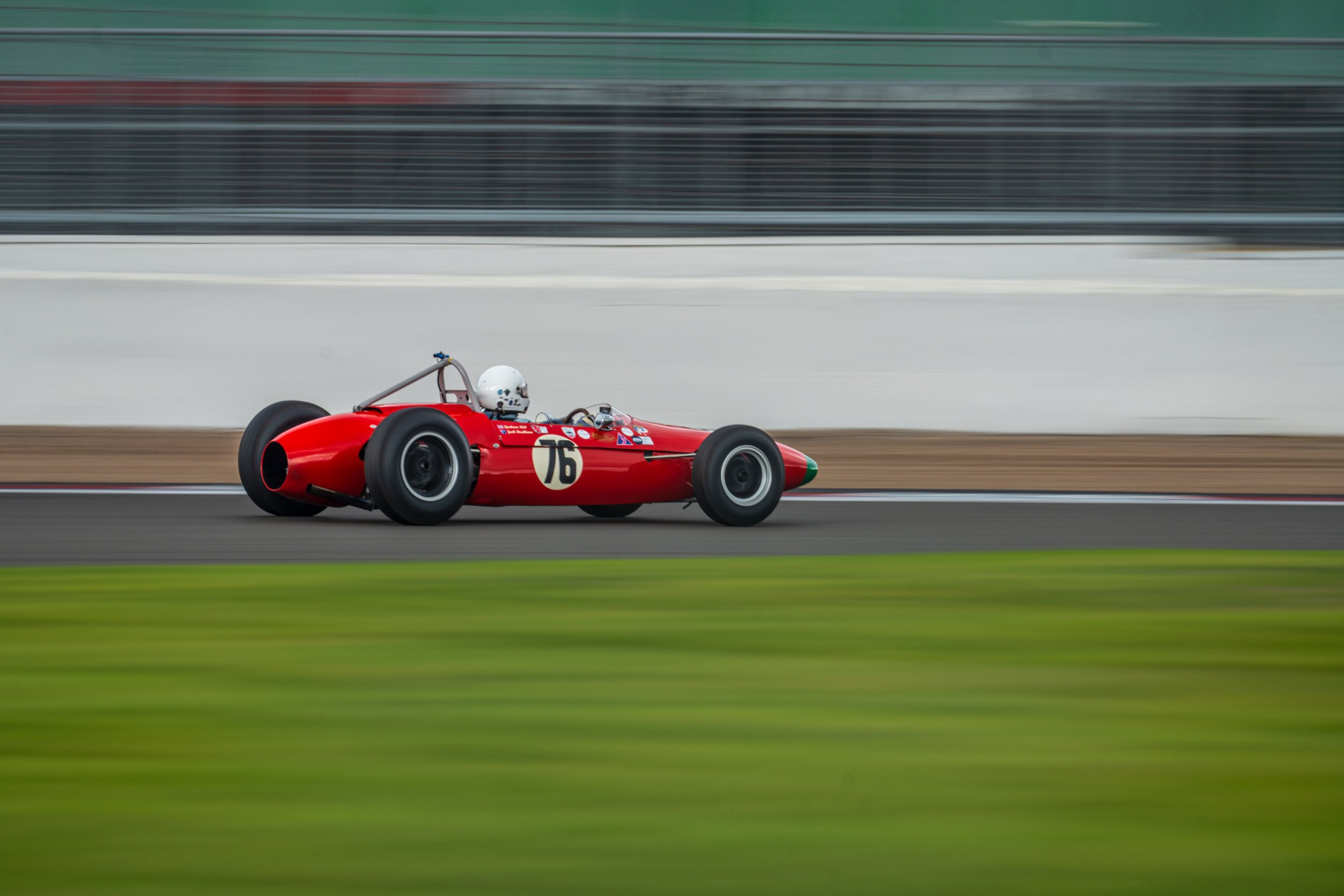 Red classic single-seater captured in a panning shot at Silverstone.