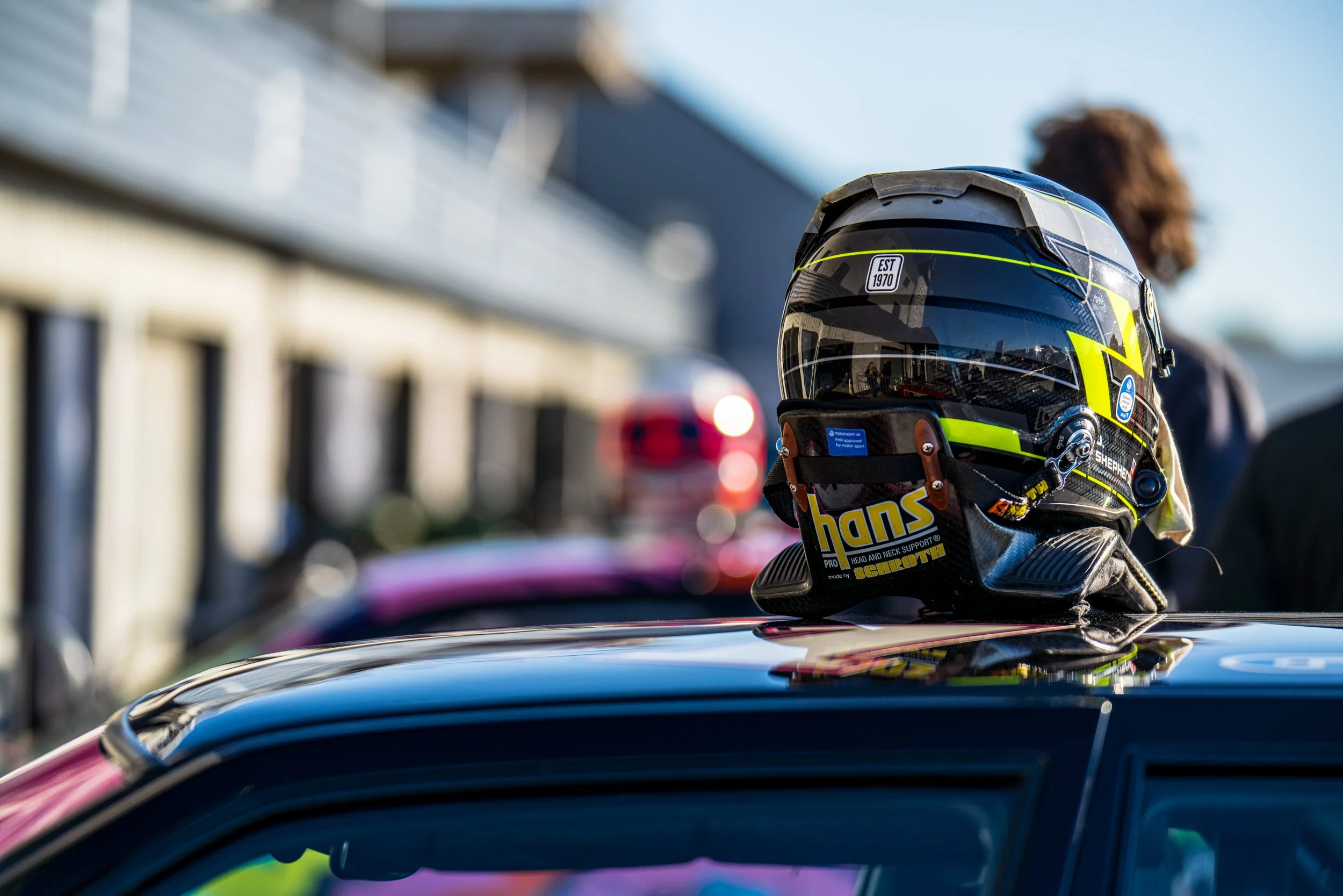 A racing helmet resting on the roof of a car at Silverstone.