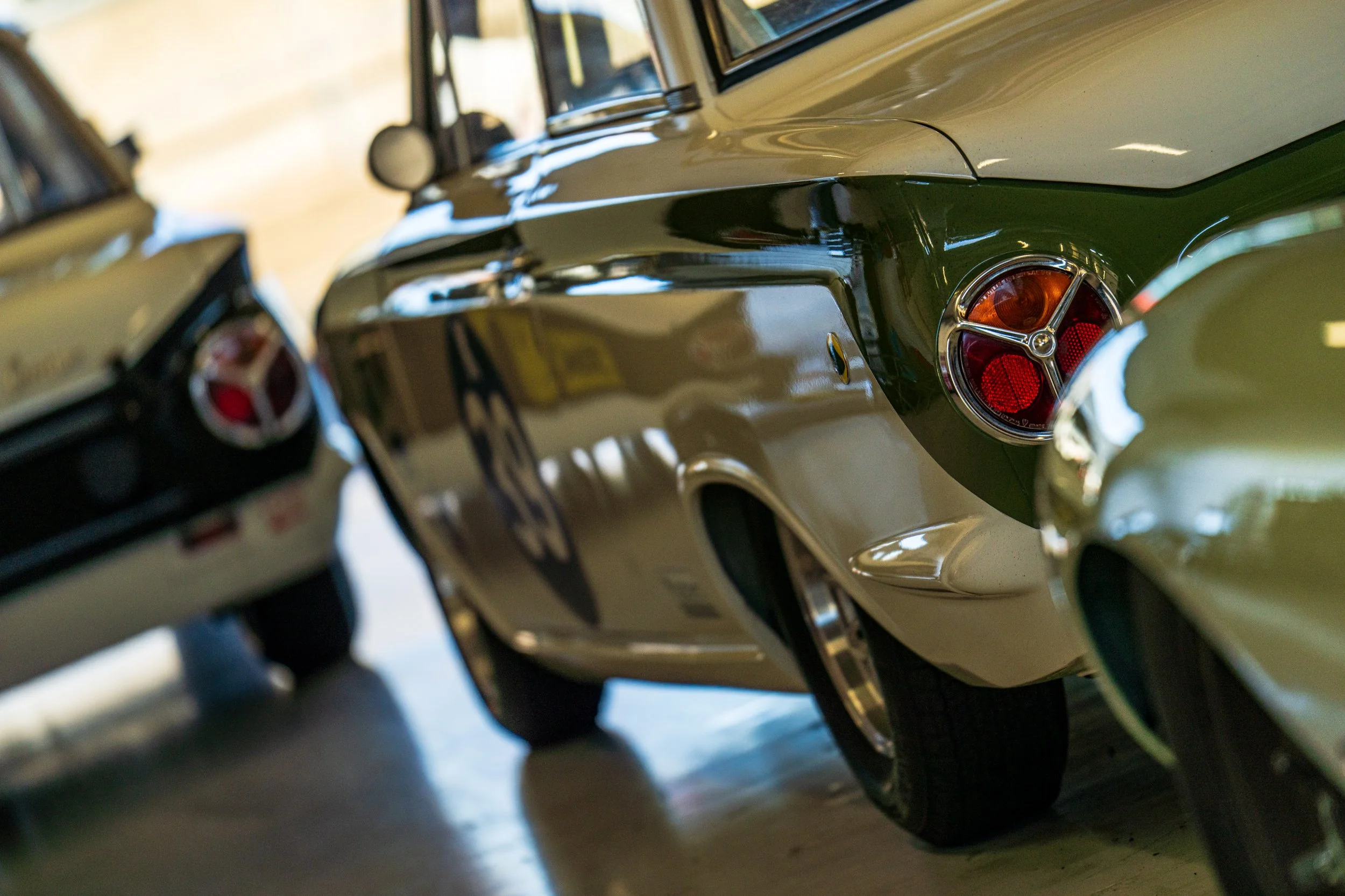 Rear bodywork and tail light of a silver classic sports car in the Silverstone paddock.