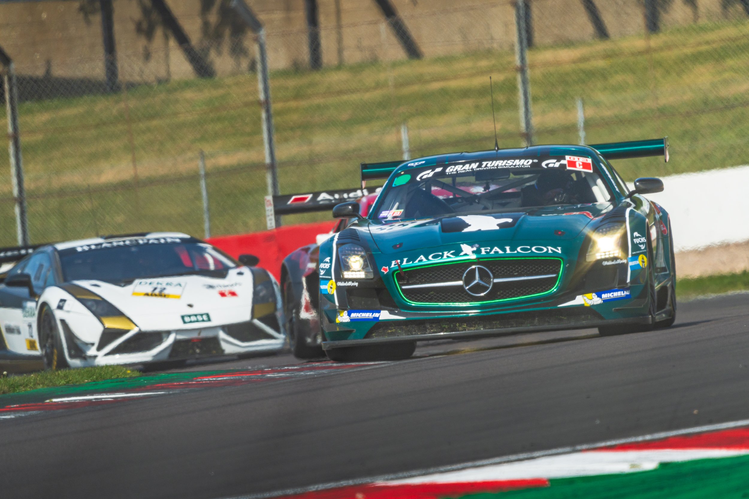 Green GT racing car among a group of cars at Donington Park.