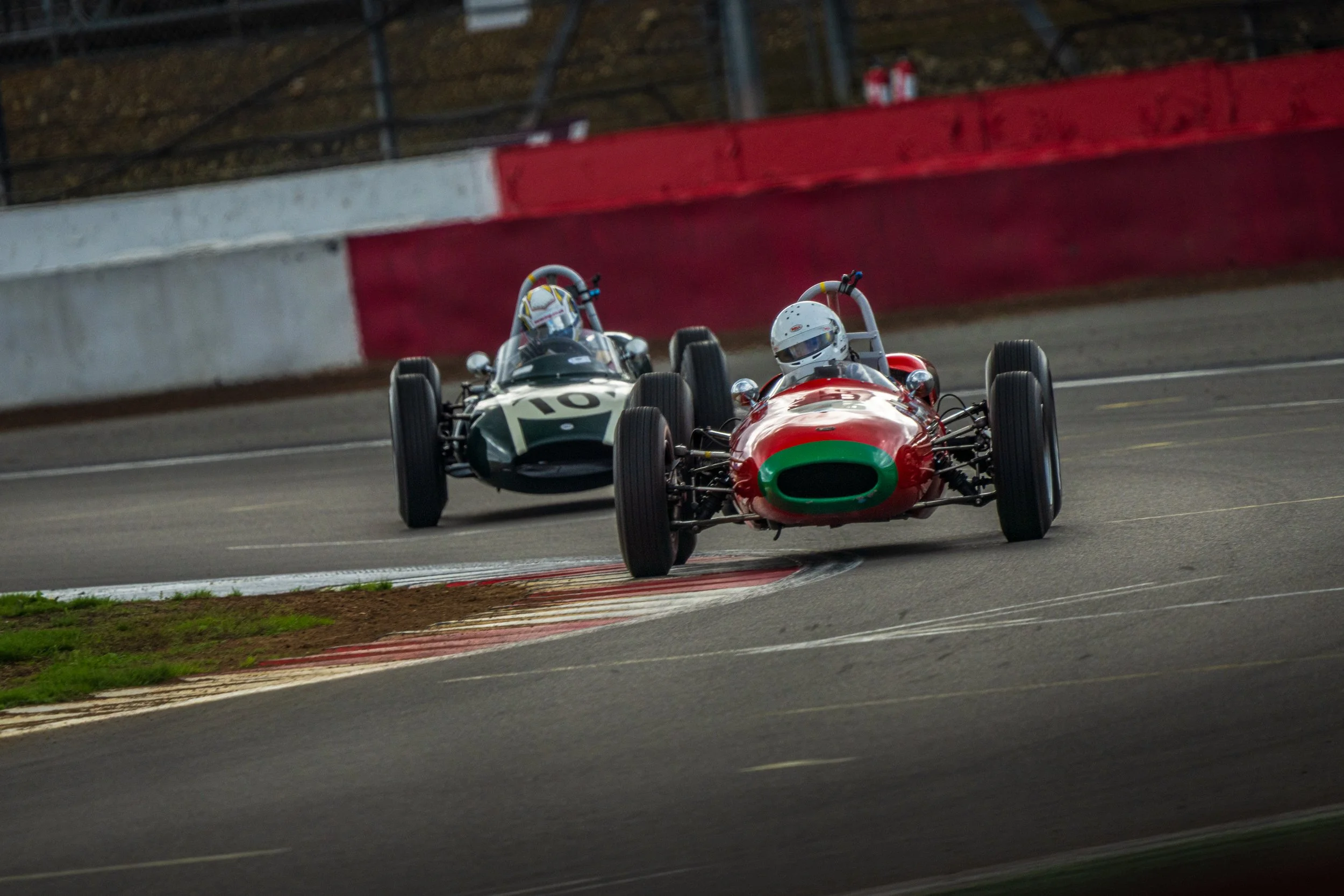 Classic single-seaters racing closely together on the Silverstone circuit.