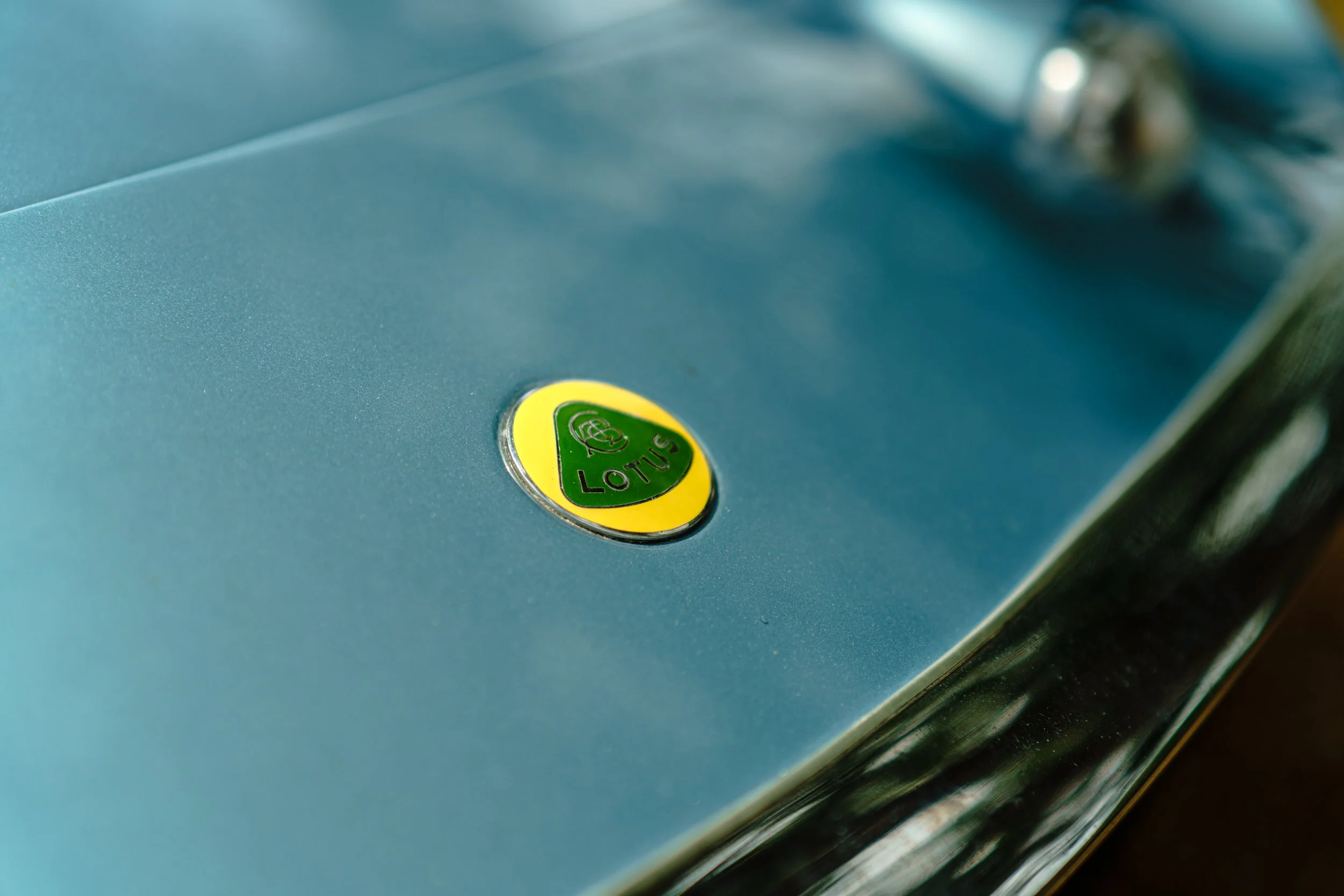 Close-up of a metallic surface with a yellow and green Lotus emblem.
