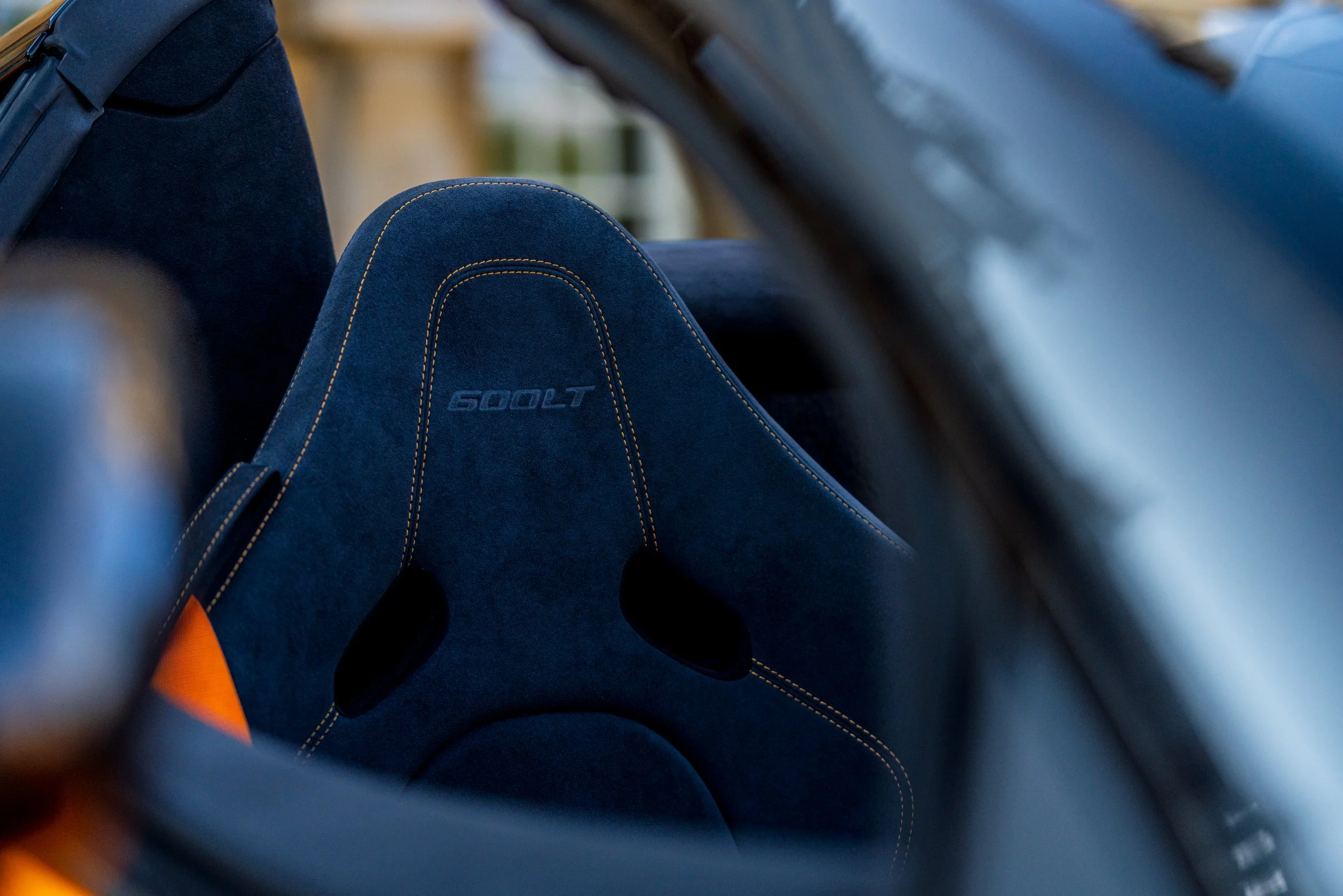 Close-up of blue car seat with yellow stitching and the word '600LT' embroidered on it, viewed from inside the vehicle.