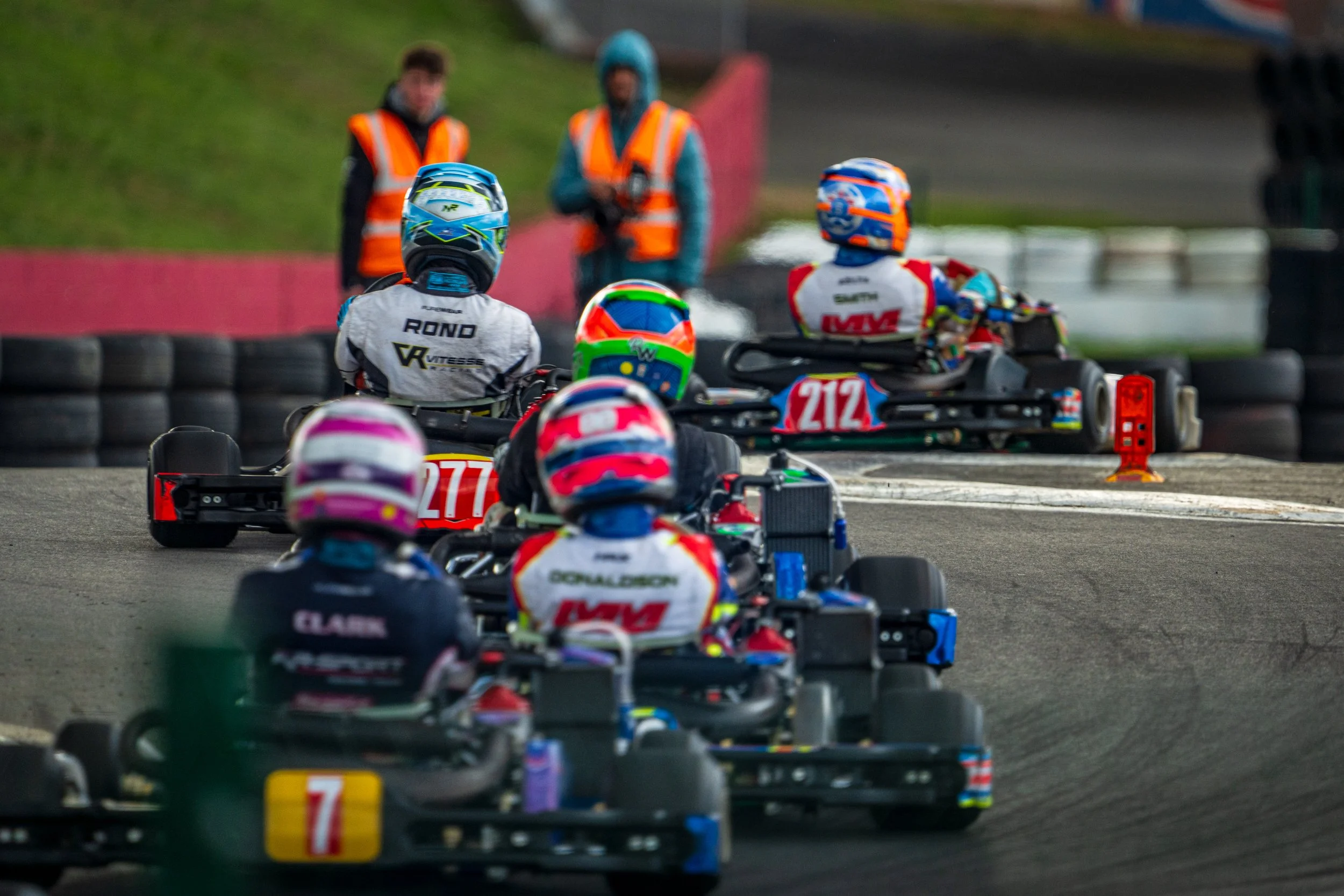 Kart racers lined up on the grid with marshals in the background at Silverstone.