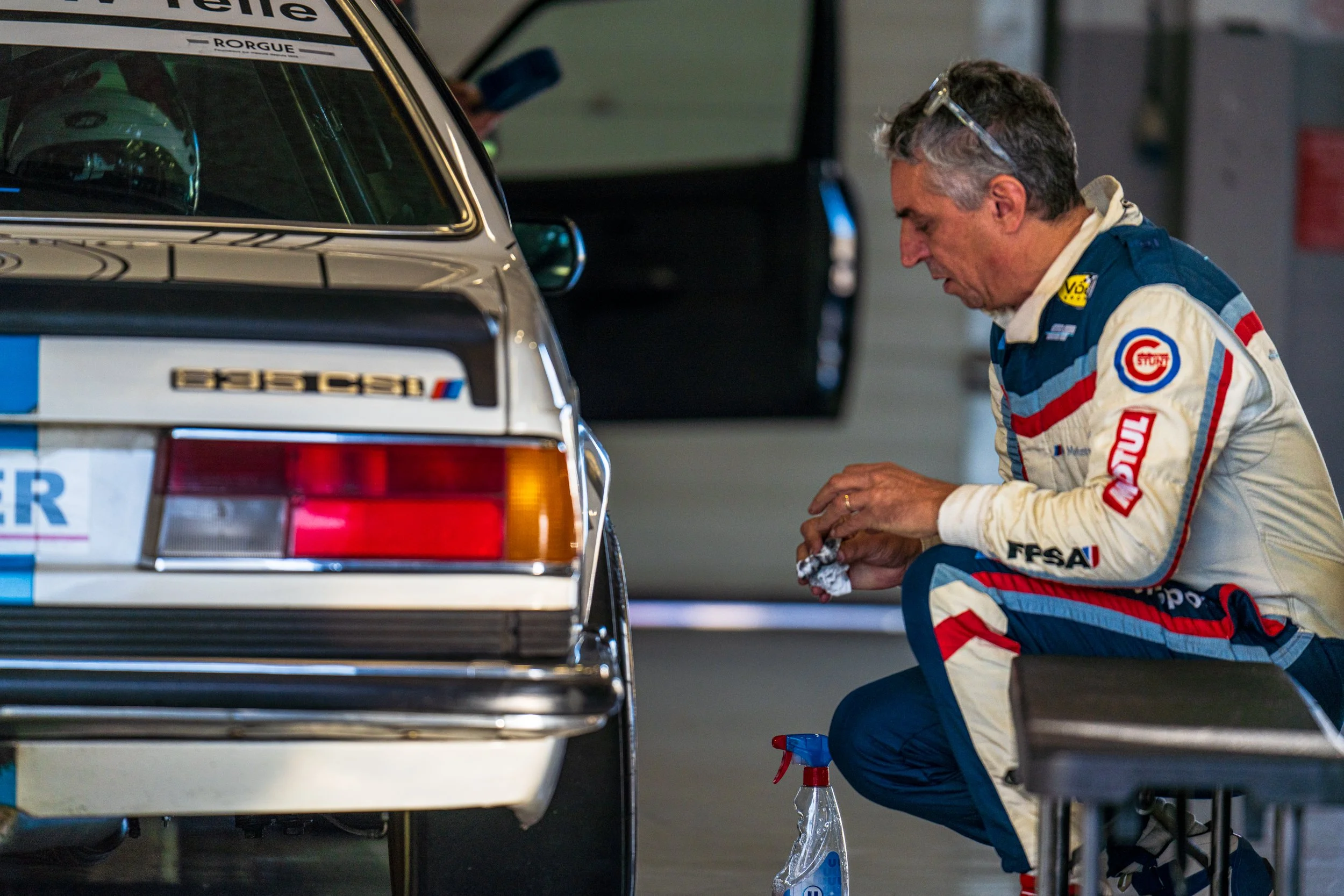 Racing driver beside the rear of a classic racing car at Silverstone.