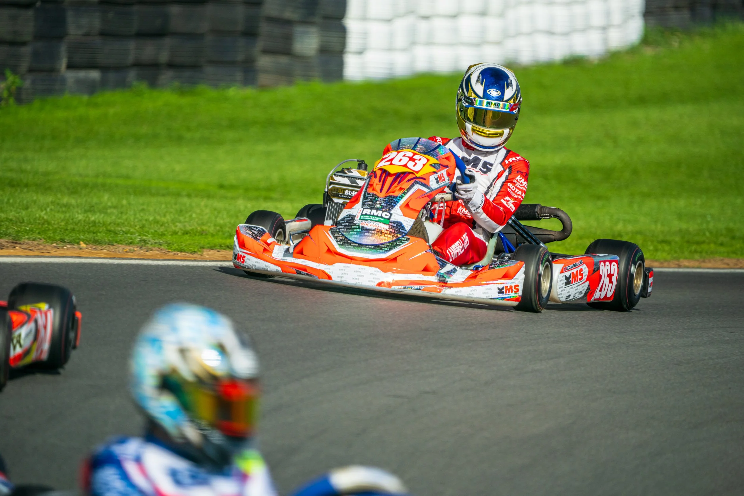 Kart racer in orange and blue equipment at Silverstone.