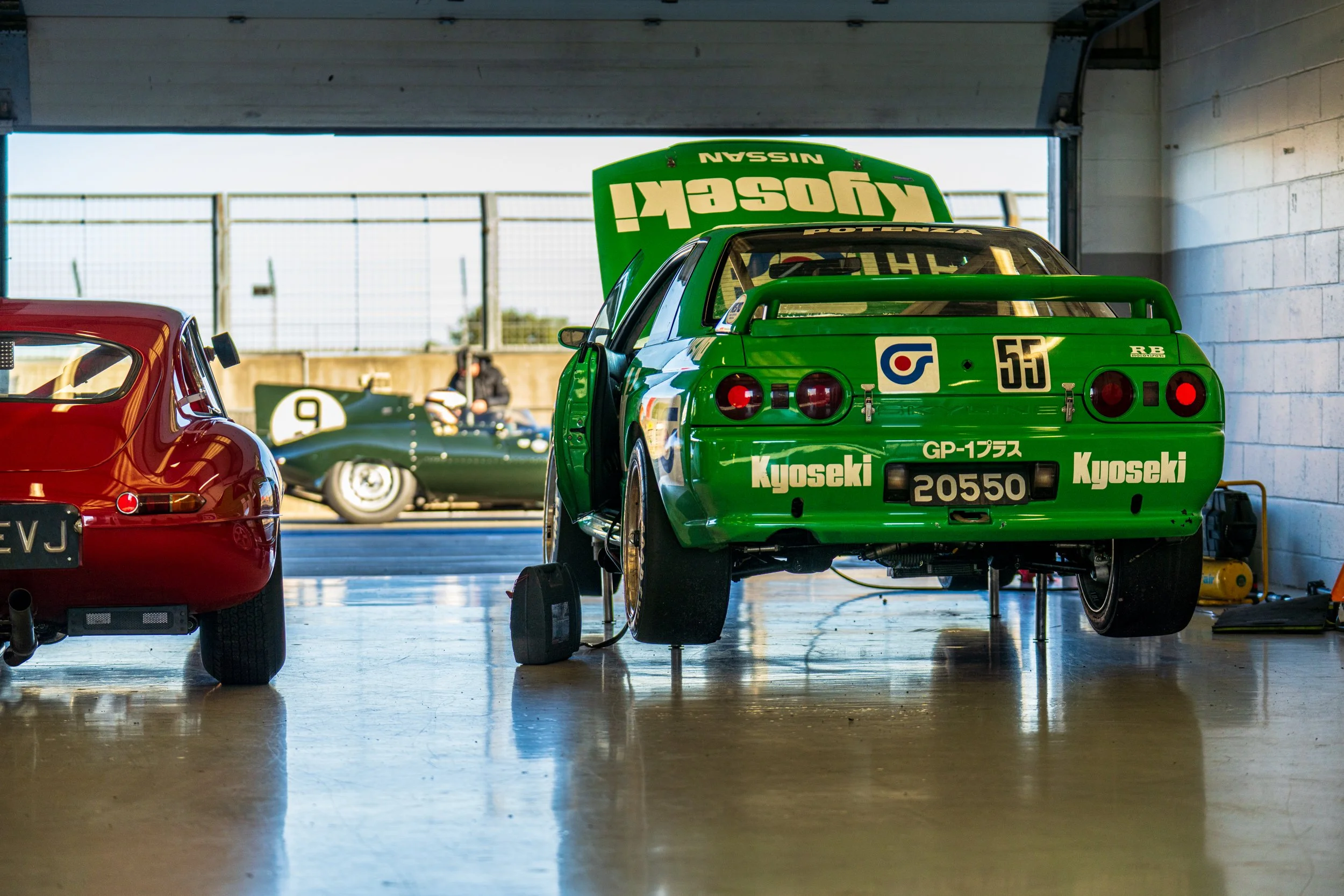 Rear of a bright green racing car inside a Silverstone pit garage.
