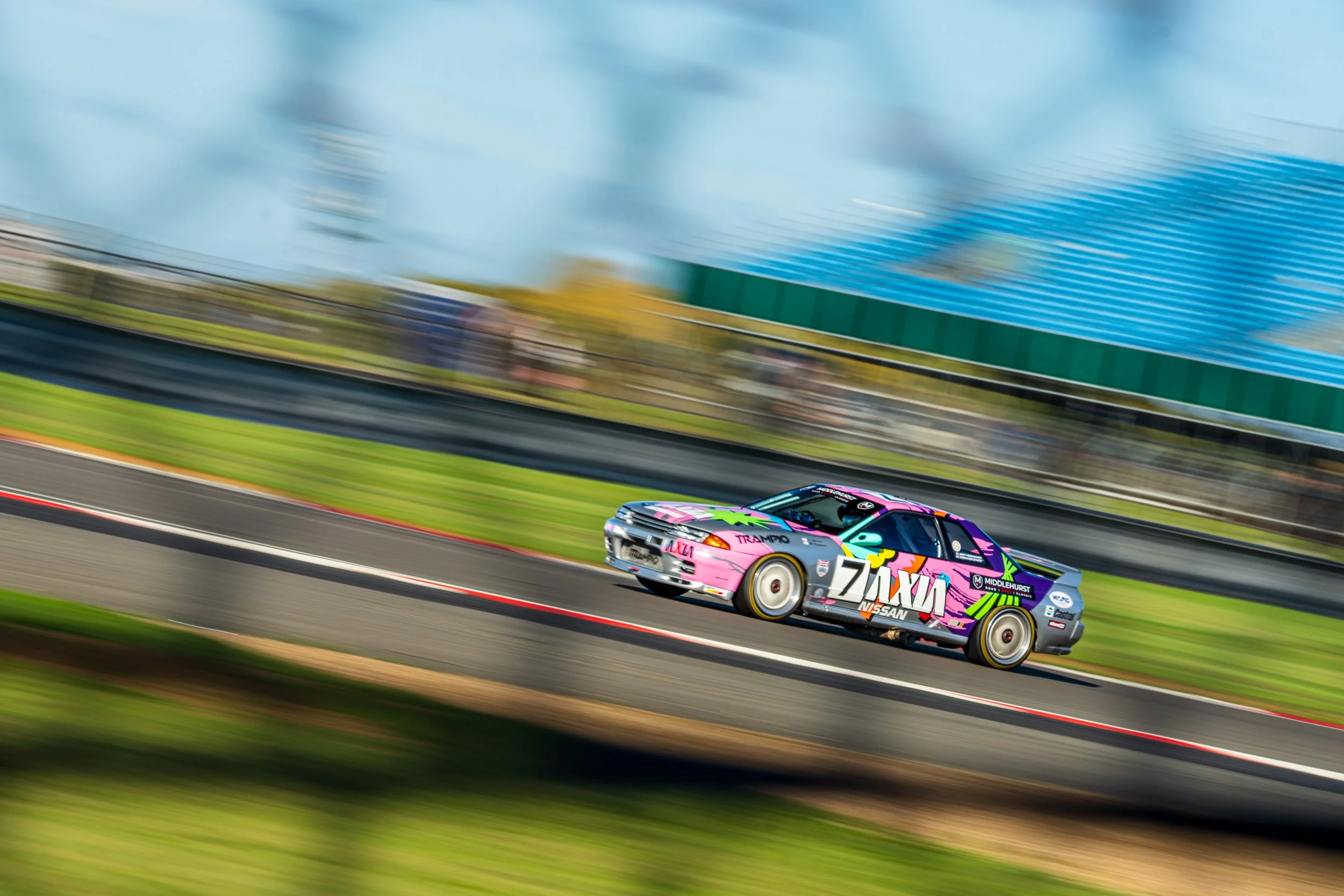 A group of racing cars seen through trackside fencing at Silverstone.