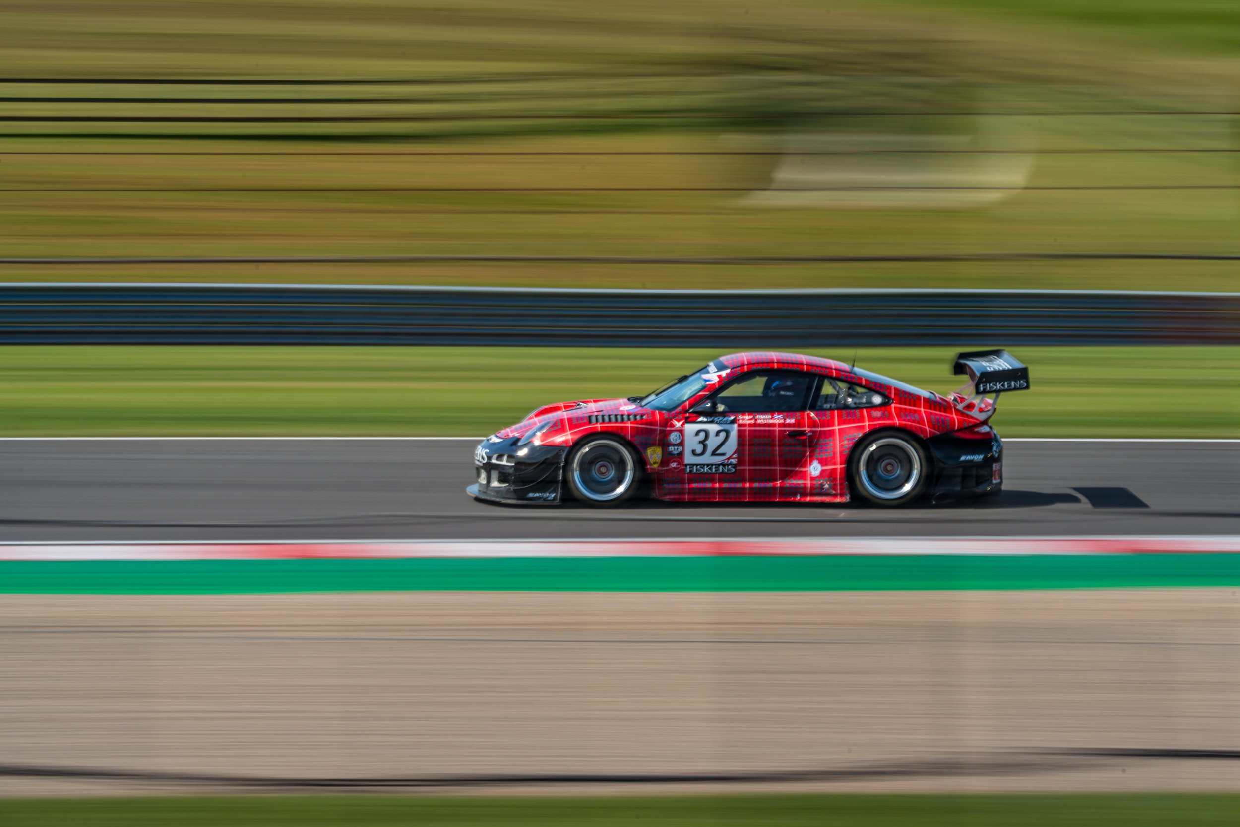 Red GT racing car captured in a side-on panning shot at Donington Park.