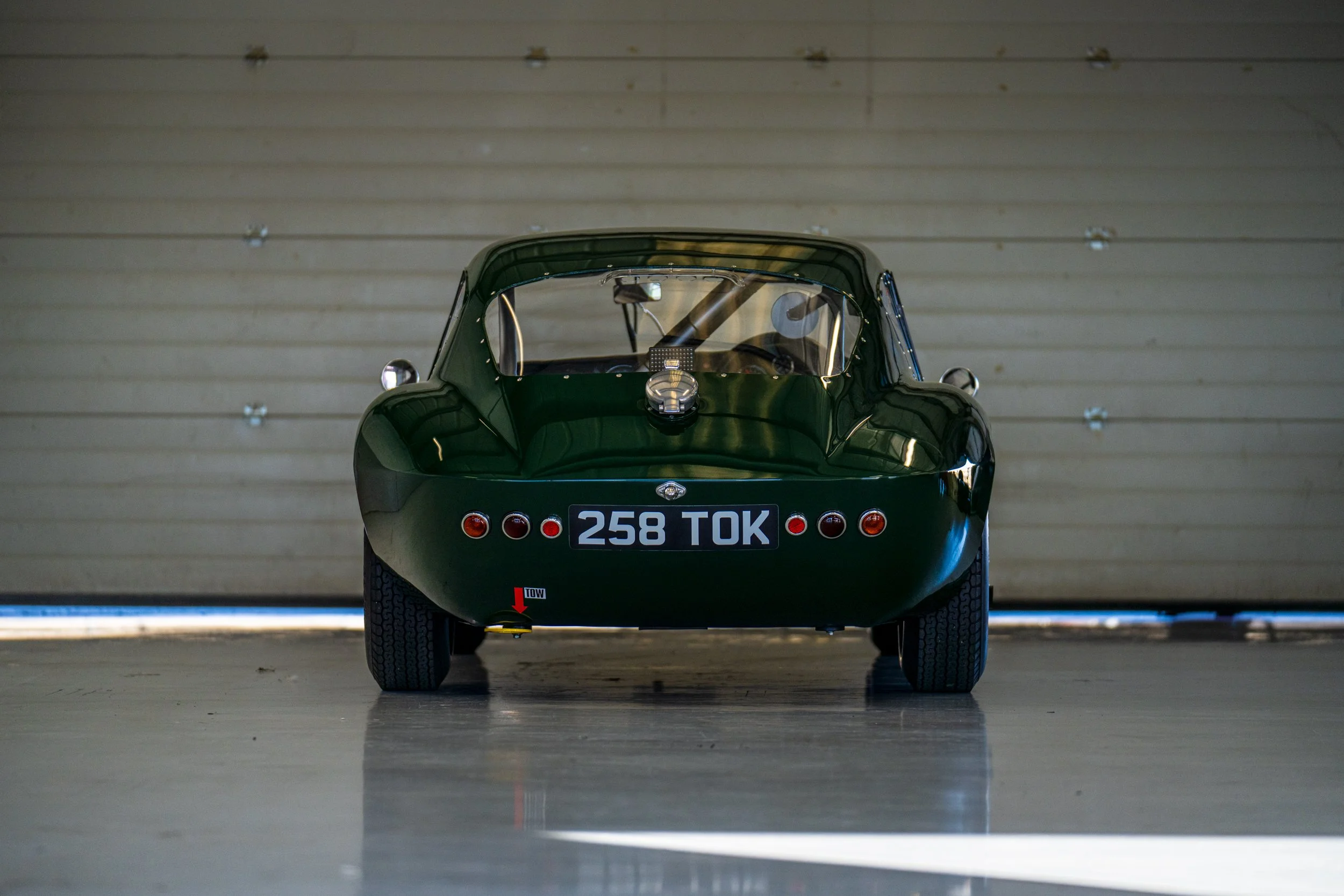 Green classic sports car parked inside a Silverstone pit garage.