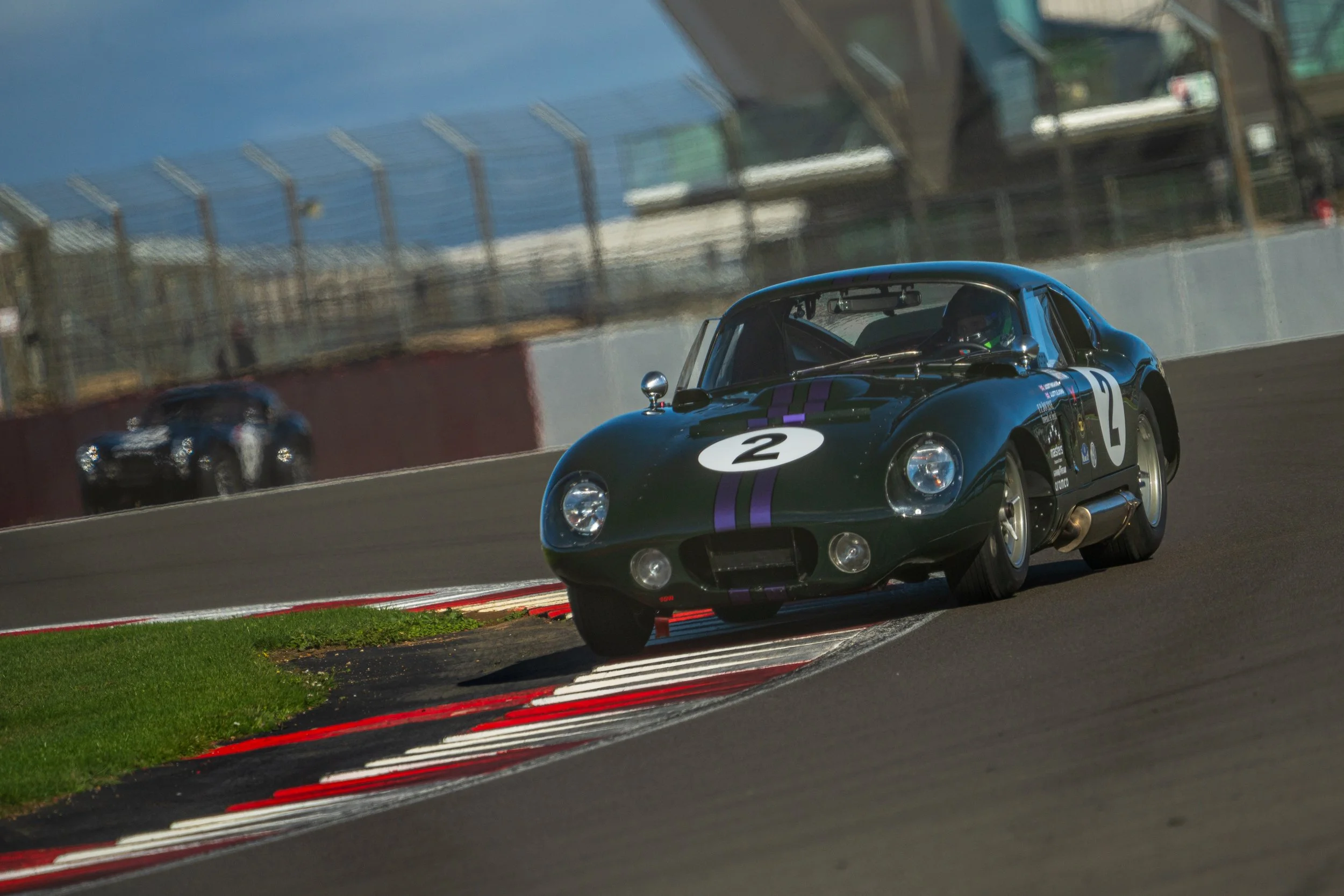 Dark green classic sports car cornering at Silverstone.