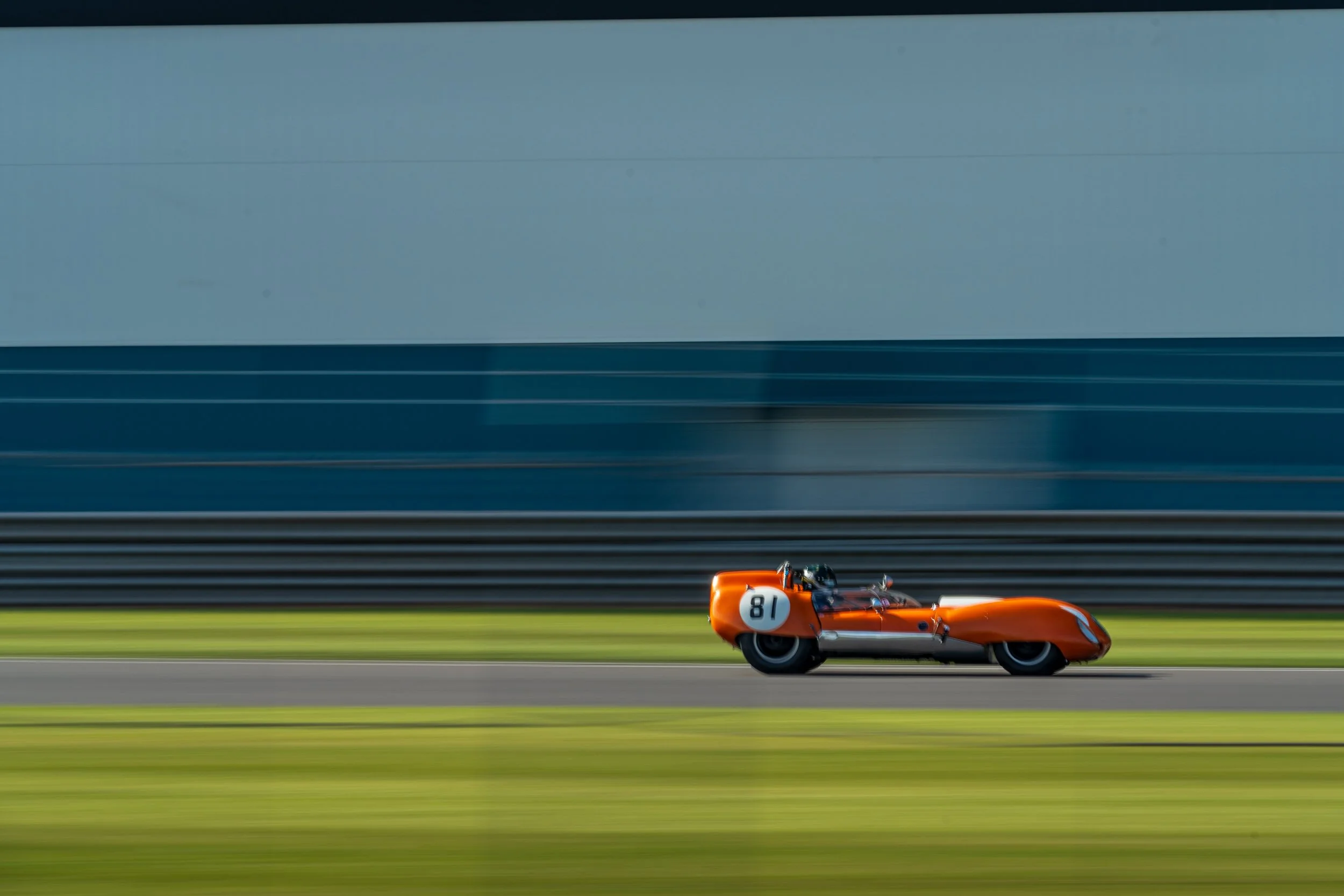 Orange racing car photographed in a panning shot at Donington Park.