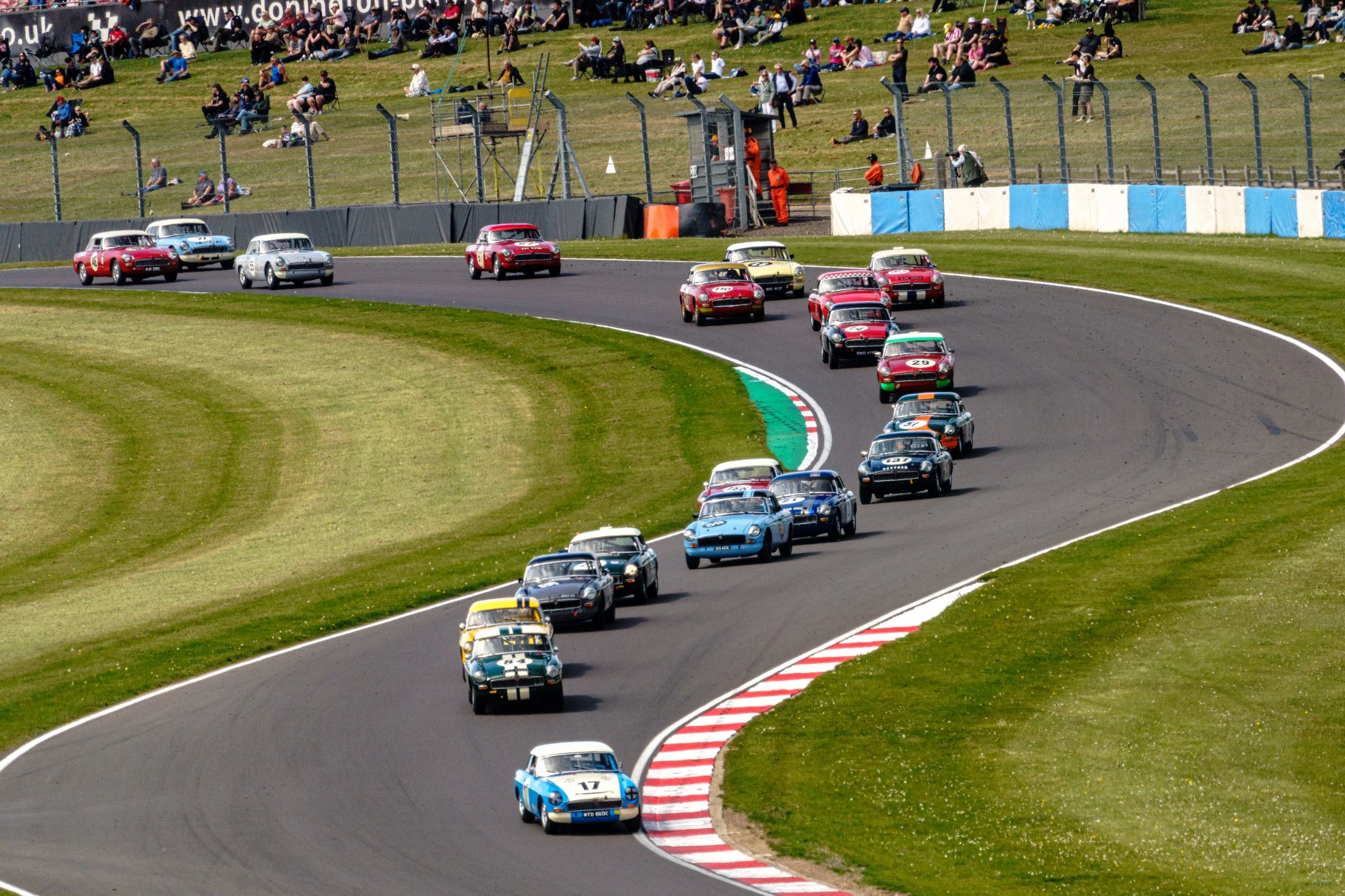 A field of classic touring cars negotiating a chicane at Donington Historic Festival.