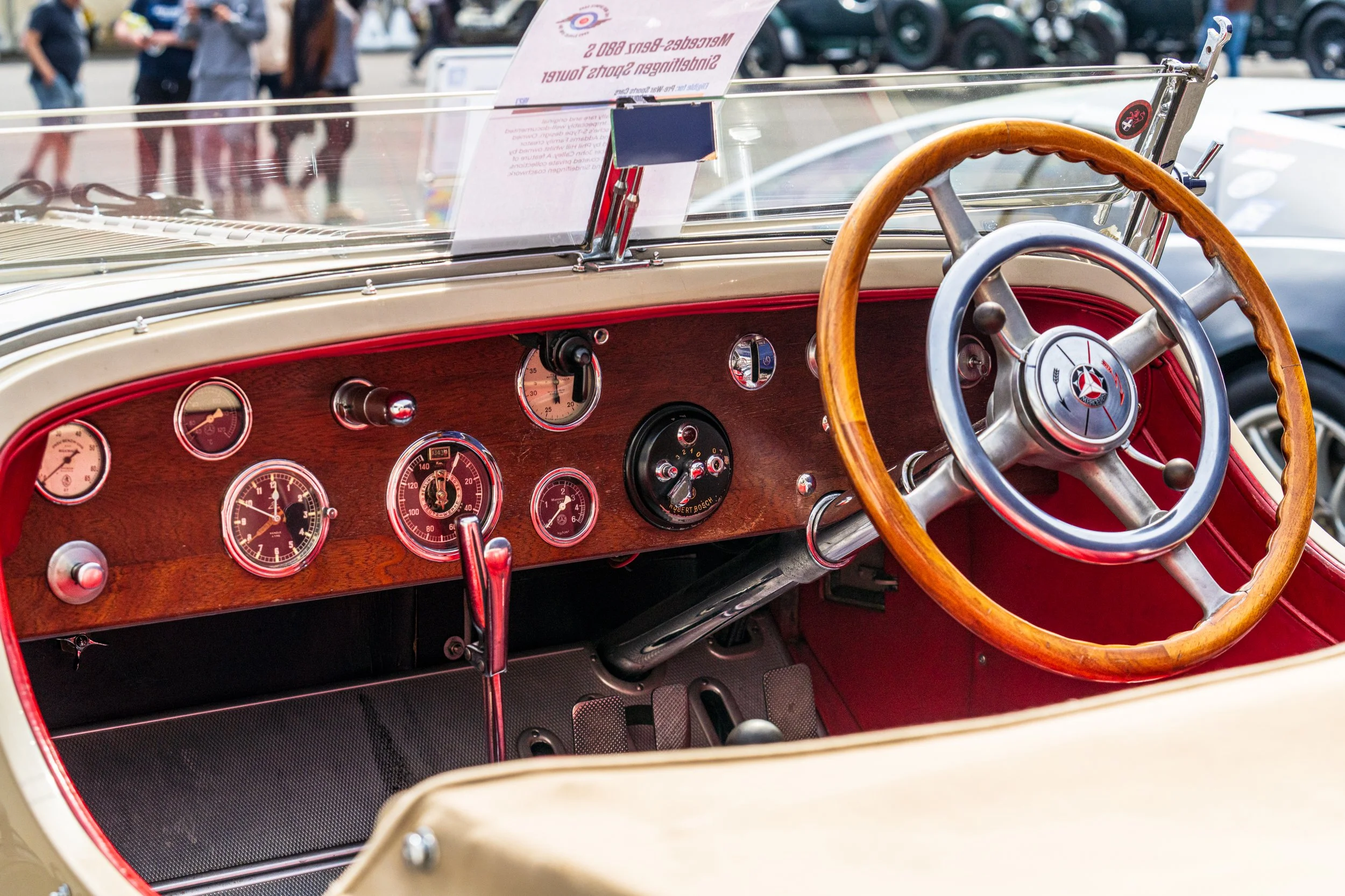 Wood-rim steering wheel and red dashboard inside a classic car at Donington Historic Festival.