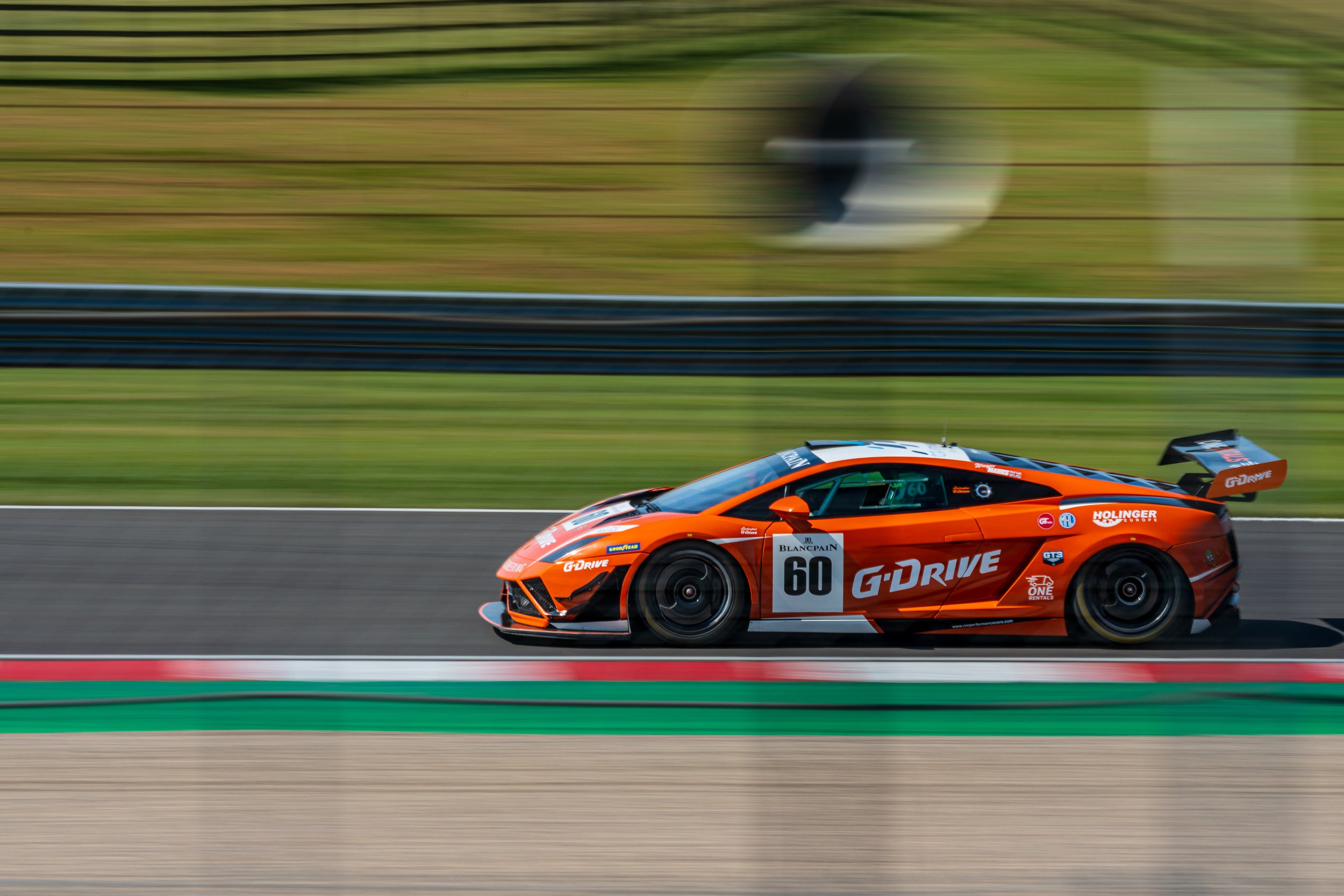 Orange McLaren GT racing car number 60 captured at speed at Donington Park.