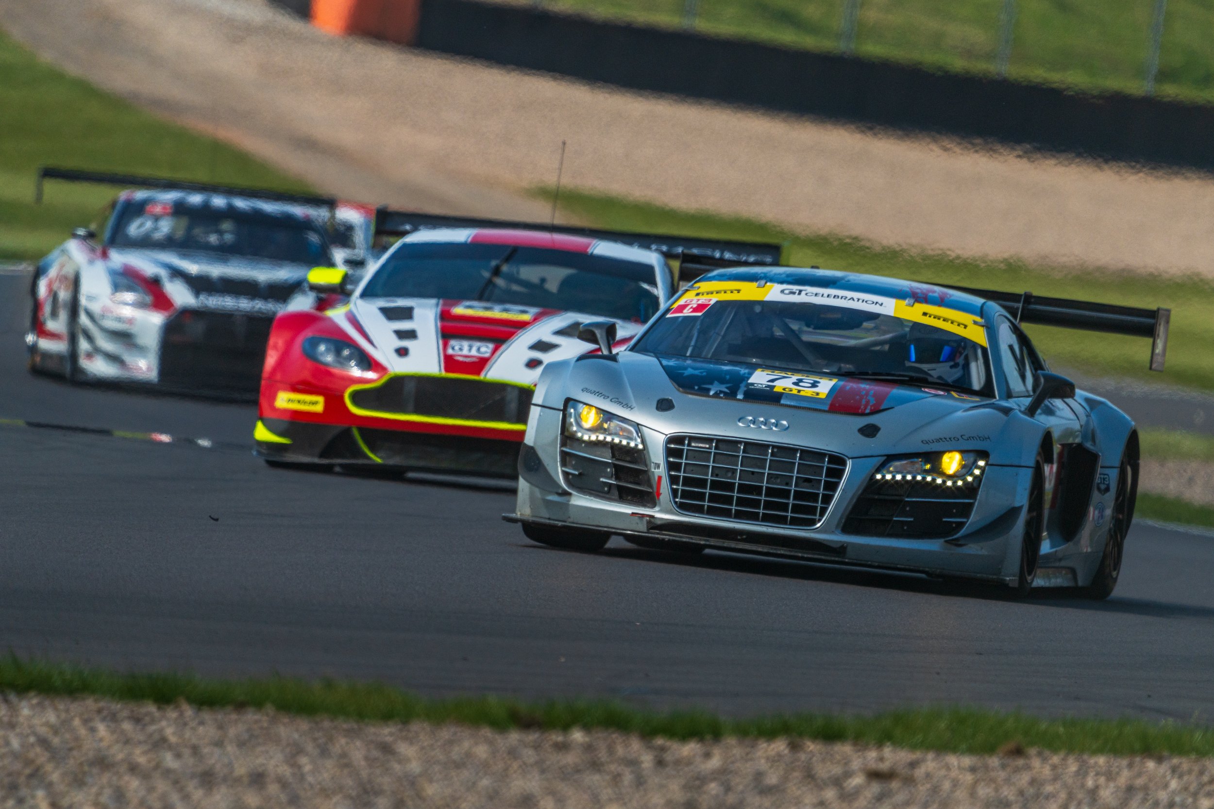 A closely packed group of GT racing cars taking a corner at Donington Park.