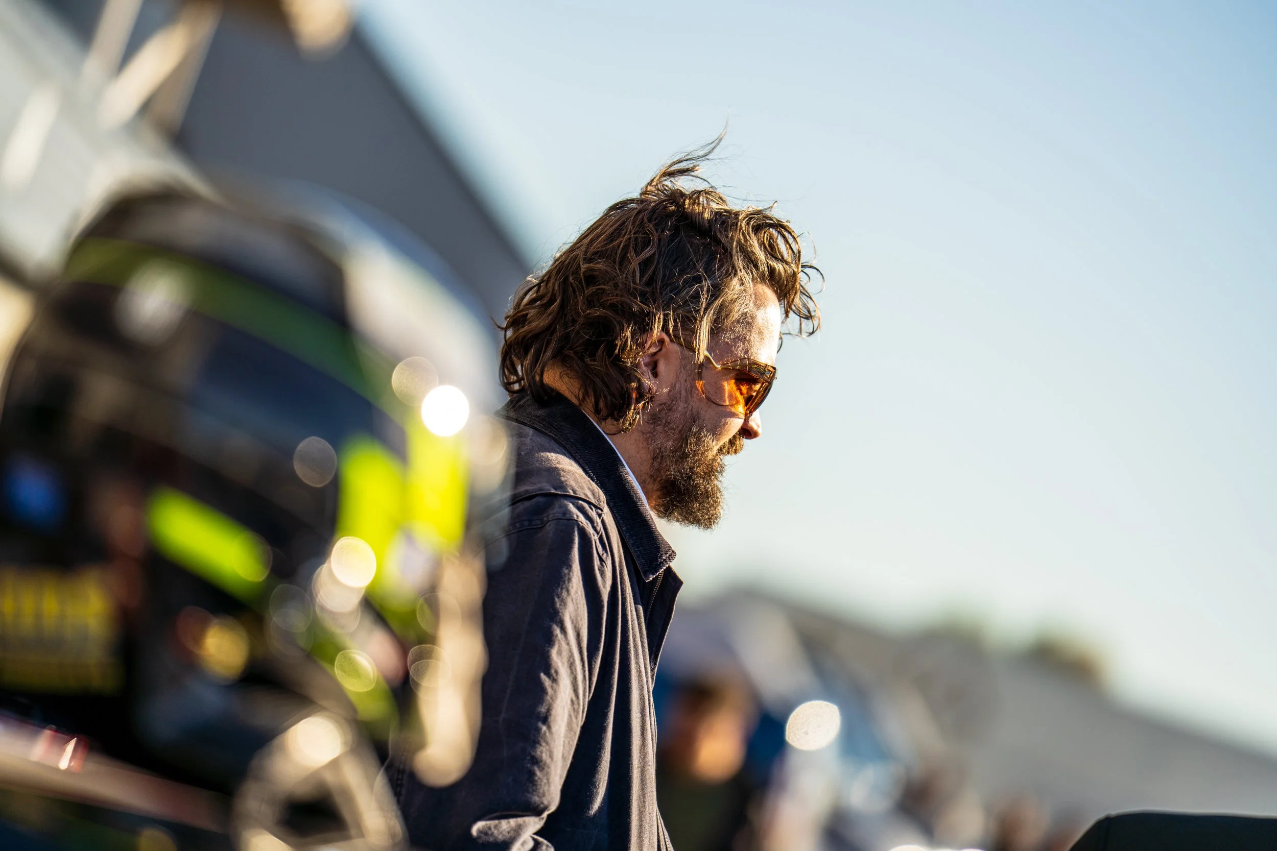 Racing driver with curly hair walking through the Silverstone paddock.
