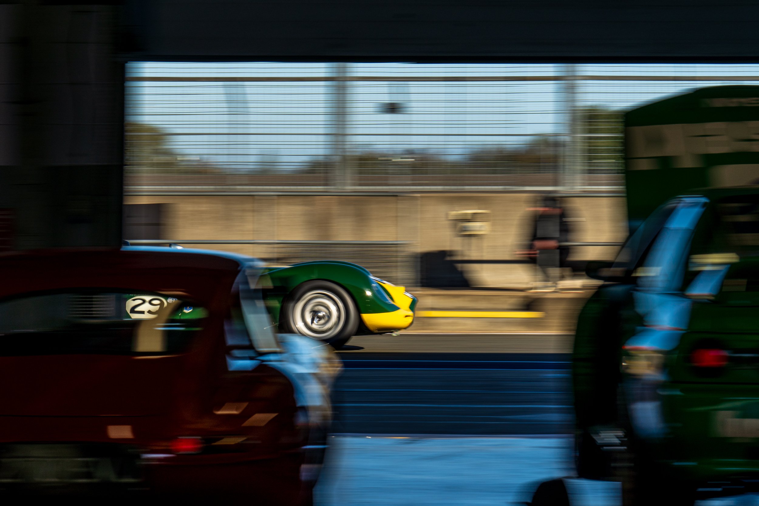 Green and yellow racing car viewed through a Silverstone pit garage.