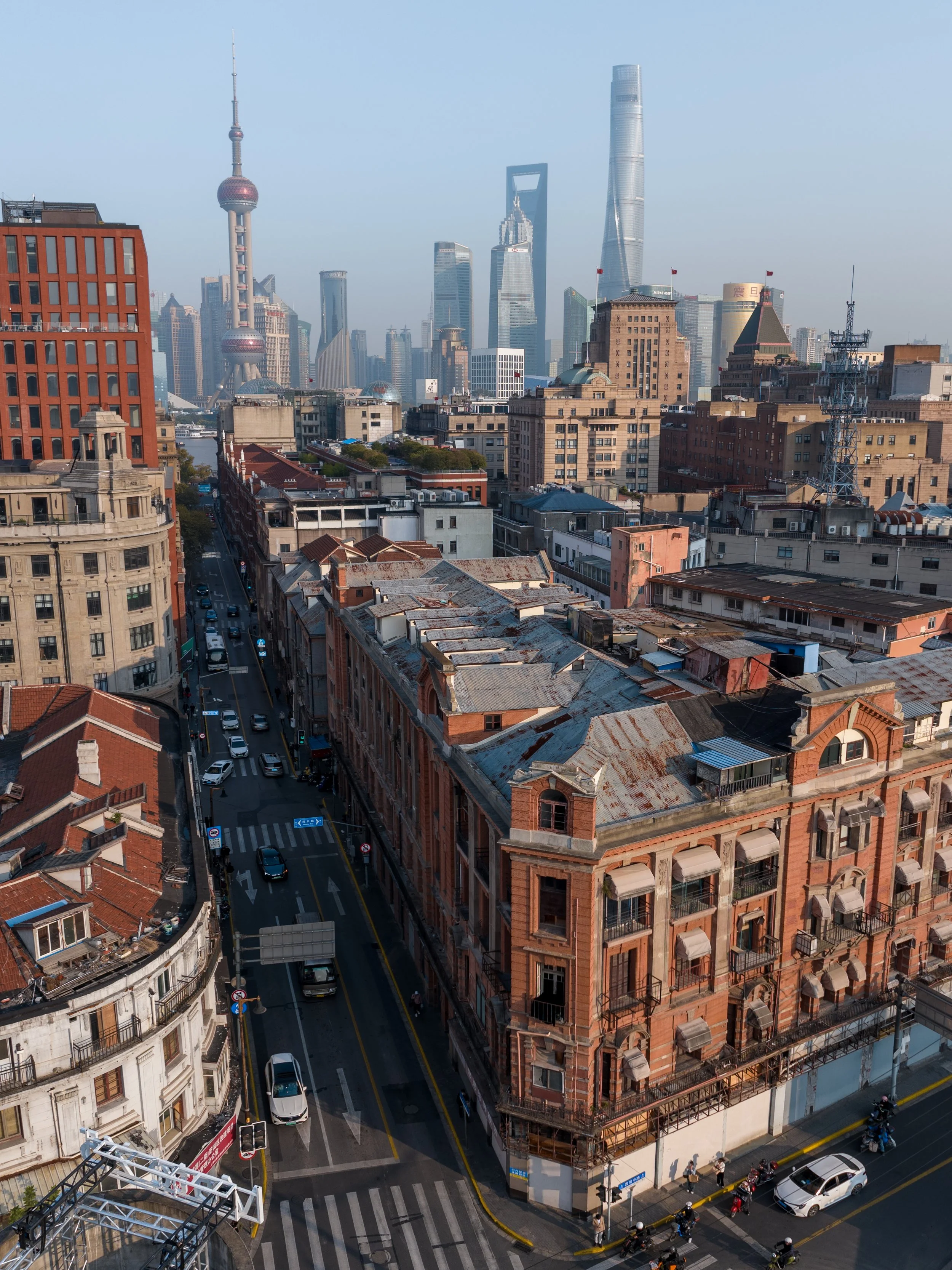 A city skyline featuring modern skyscrapers and older brick buildings, with cars and motorcycles on the streets below.