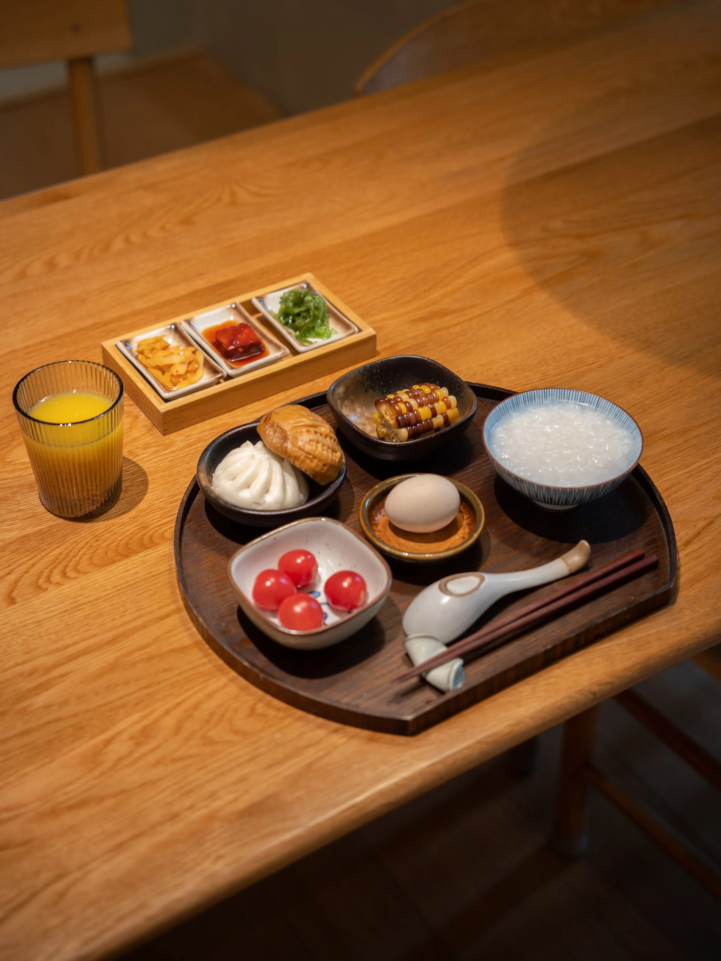 Traditional Chinese breakfast tray with eggs, doughnuts, and condiments on a wooden table.