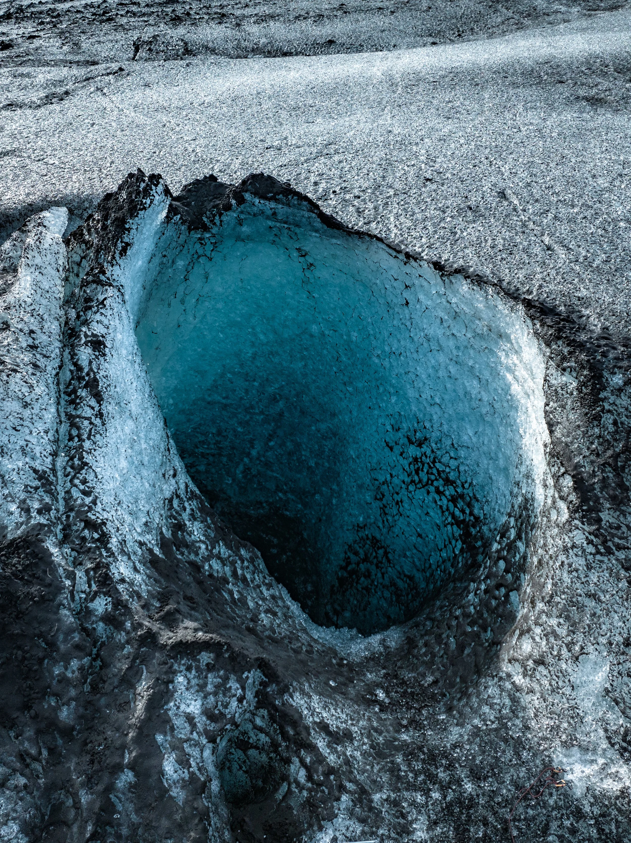An icy crevasse in the glacier with jagged ice walls and a deep blue interior.