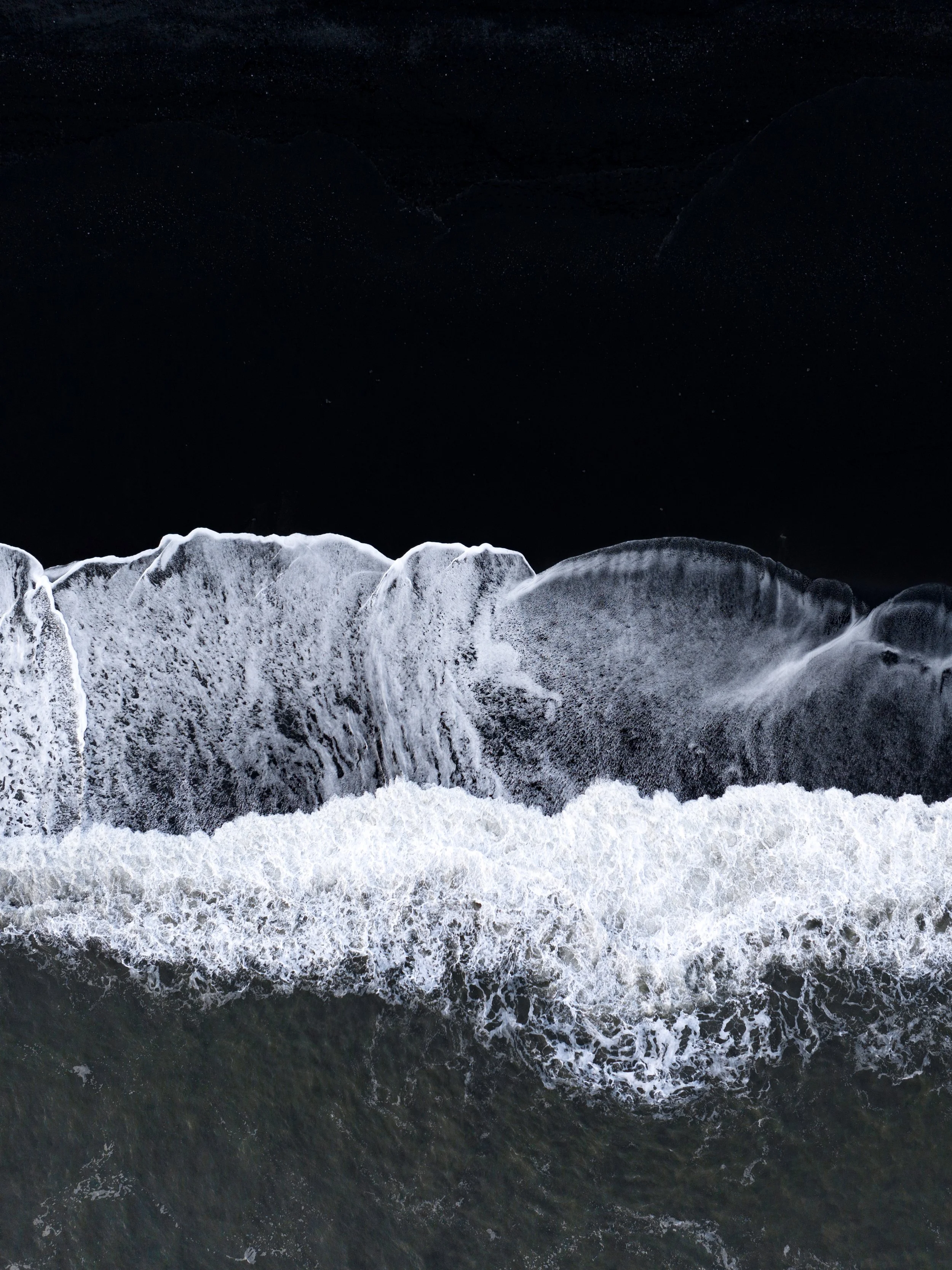 Bird's-eye view of a waterfall cascading into the dark river below at night.