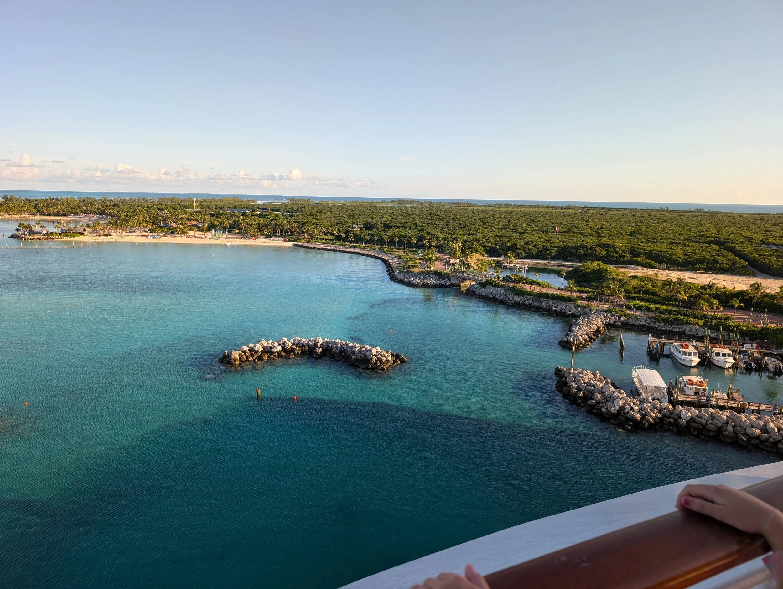 Tropical marina with turquoise water, a sandy beach, and boats near the shore.