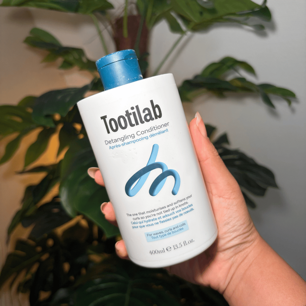 Hairstylist Lala houdt een blauw met witte flacon Tootilab Detangling Conditioner vast