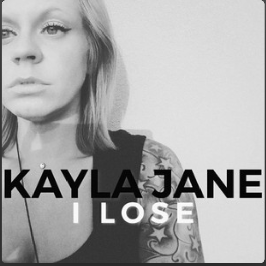 Black and white photo of a woman with shoulder-length hair, wearing a black top, with visible tattoos on her arm, and the text 'KAYLA JANE I LOSE' below her face.