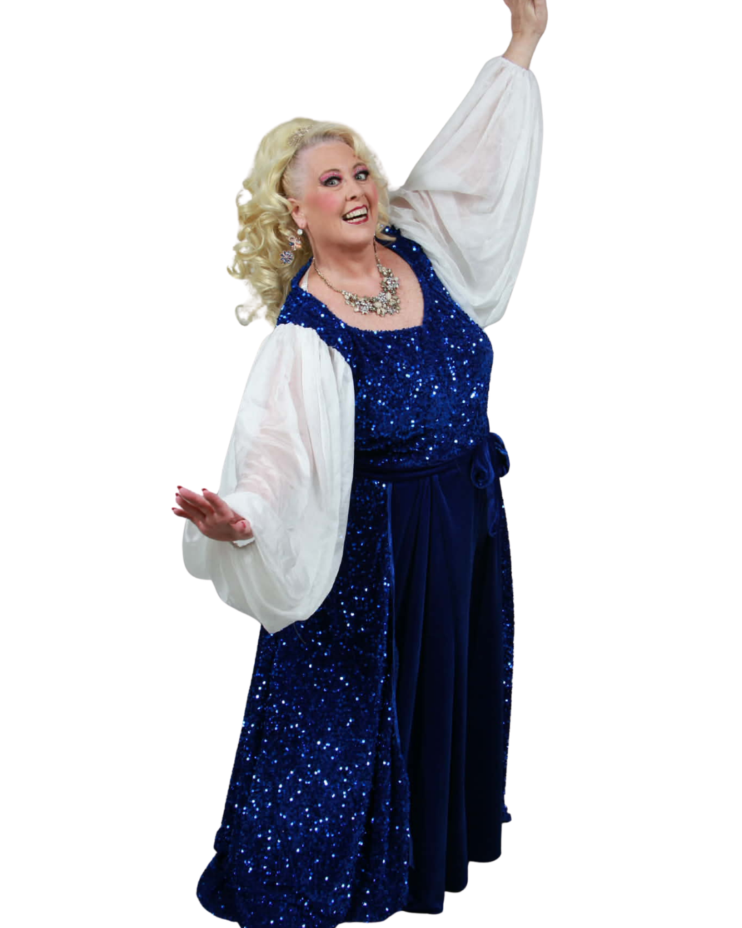 A smiling woman with blonde curly hair wearing a sparkly blue gown with puffy white sleeves, a necklace, and earrings, posed with arms raised against a white background.