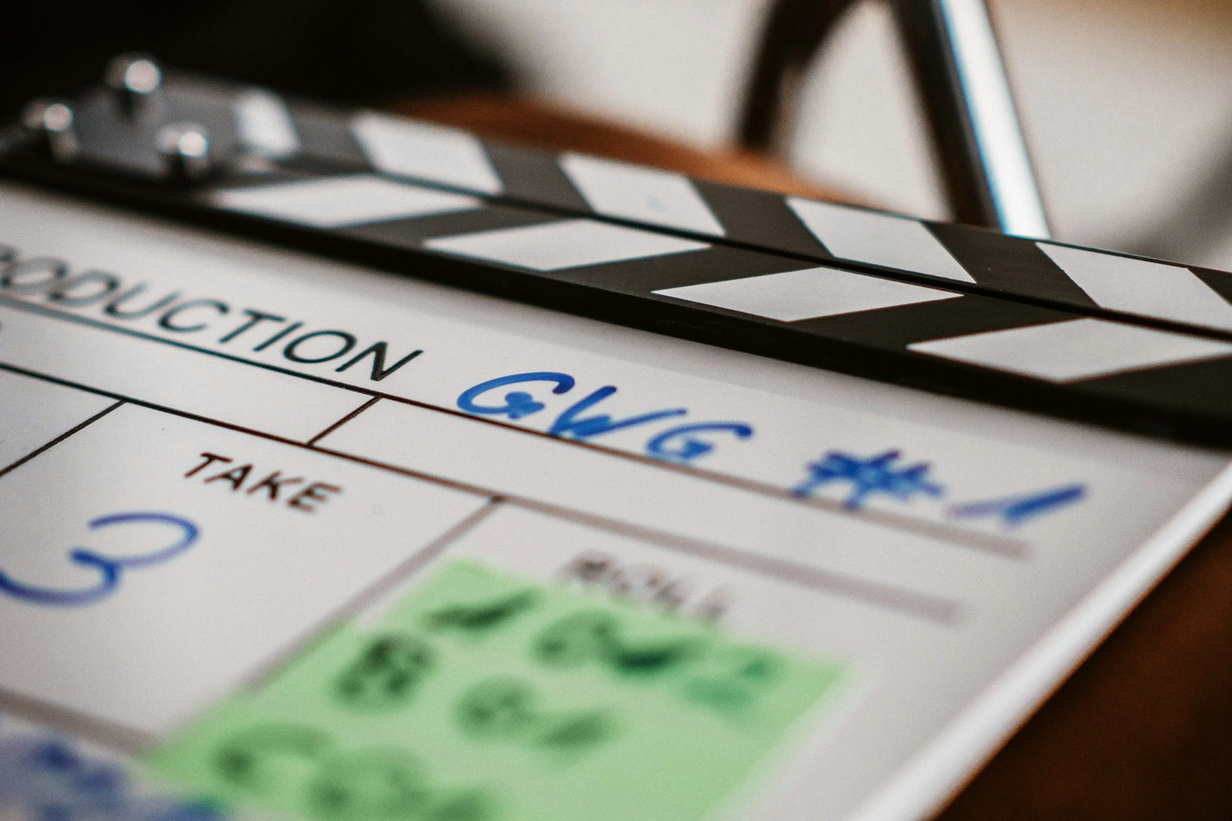 Close-up of a clapperboard, with text including 'PRODUCTION' and 'TAKE' visible.