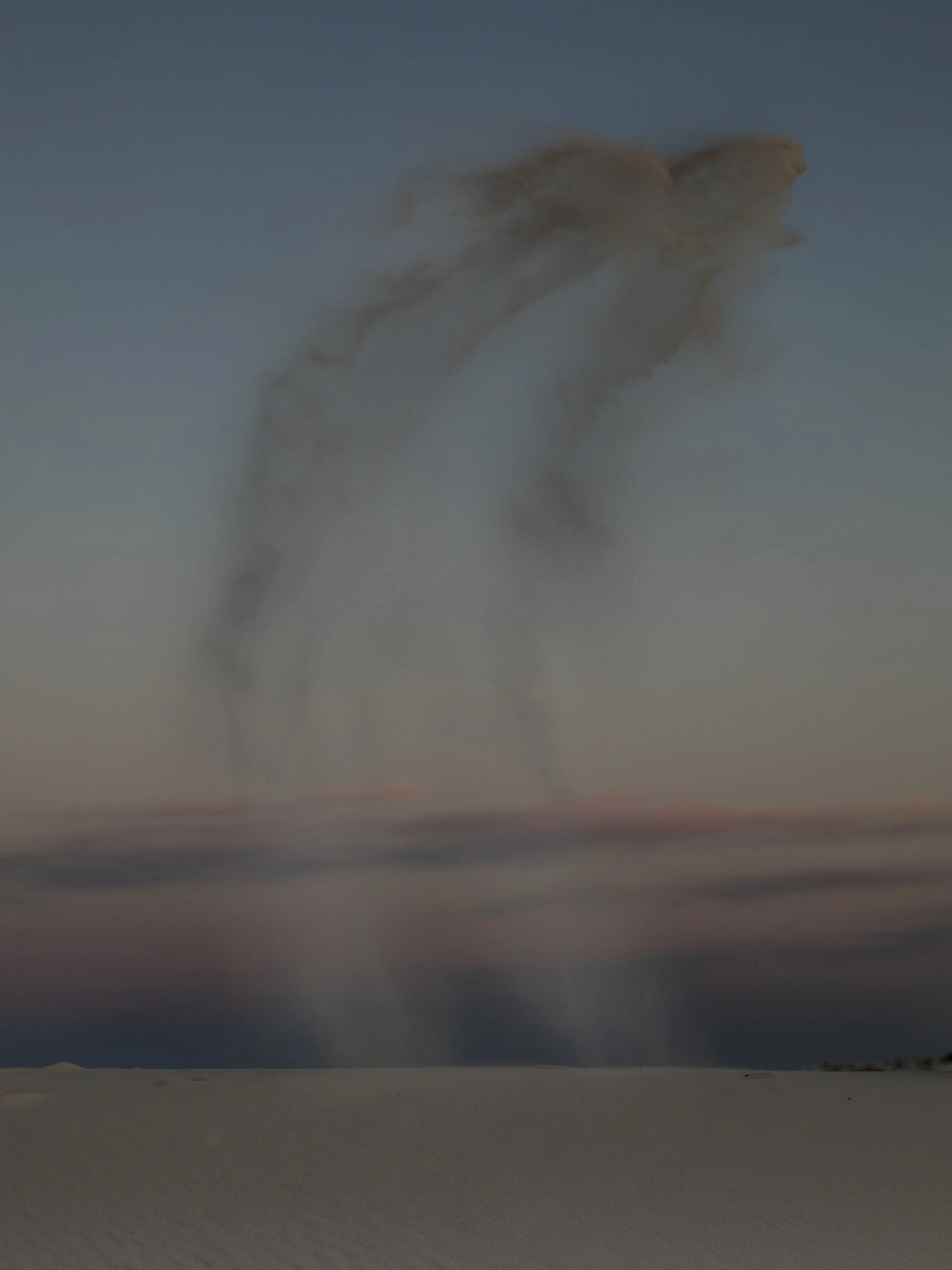 A desert landscape at dusk with a cloud of dust in the sky.