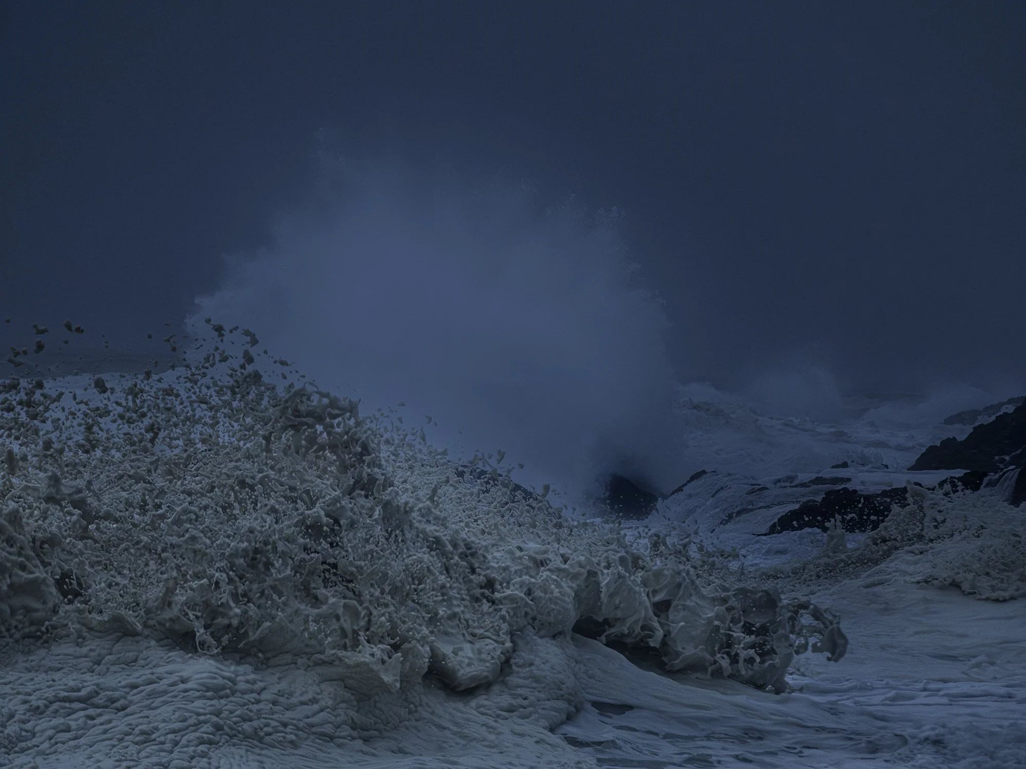 A scene of icy water with rocks and snow, possibly a frozen or partially frozen landscape with cloudy sky.