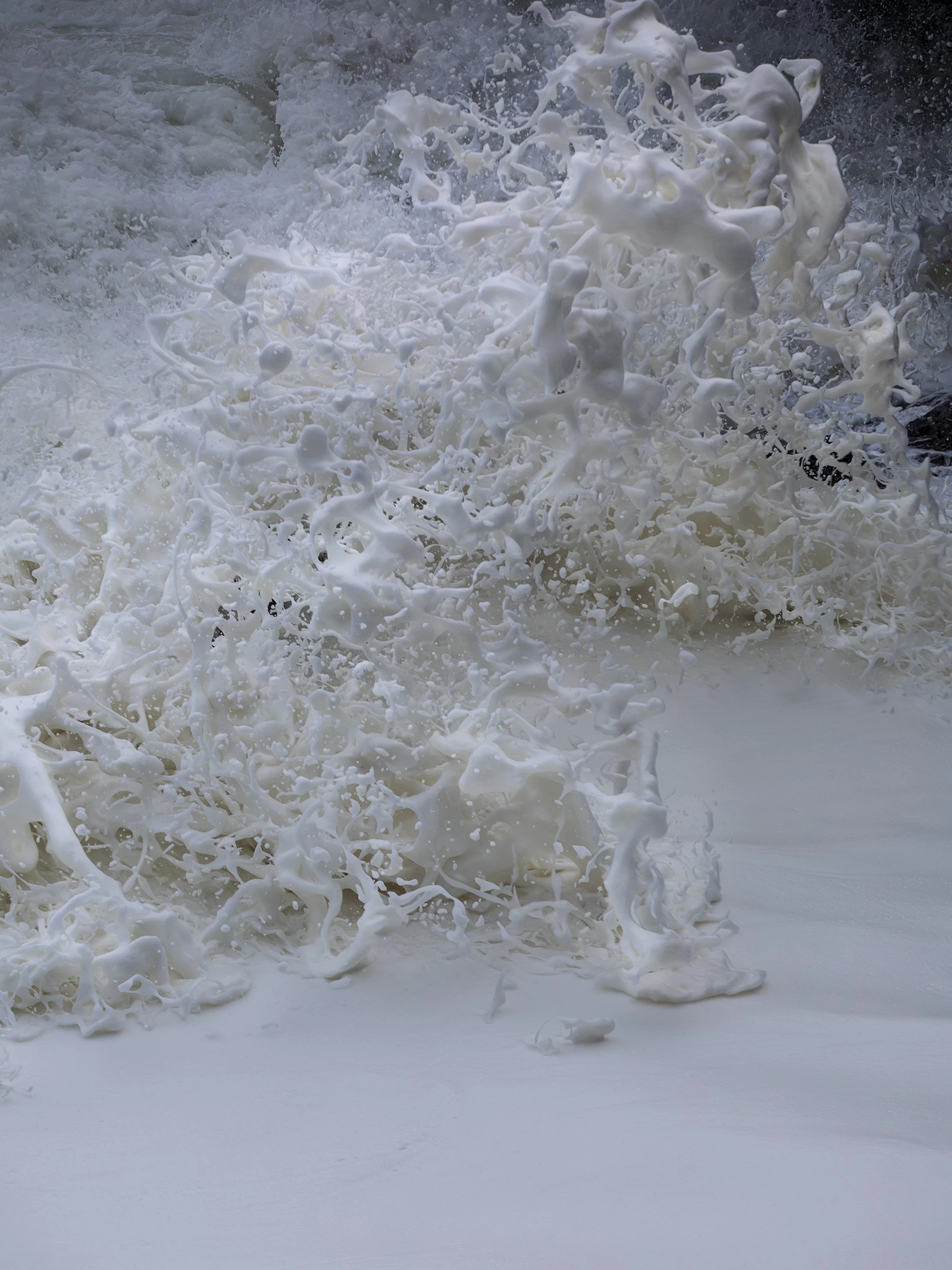 Waves crashing onto the shore with white foam and spray in the ocean.