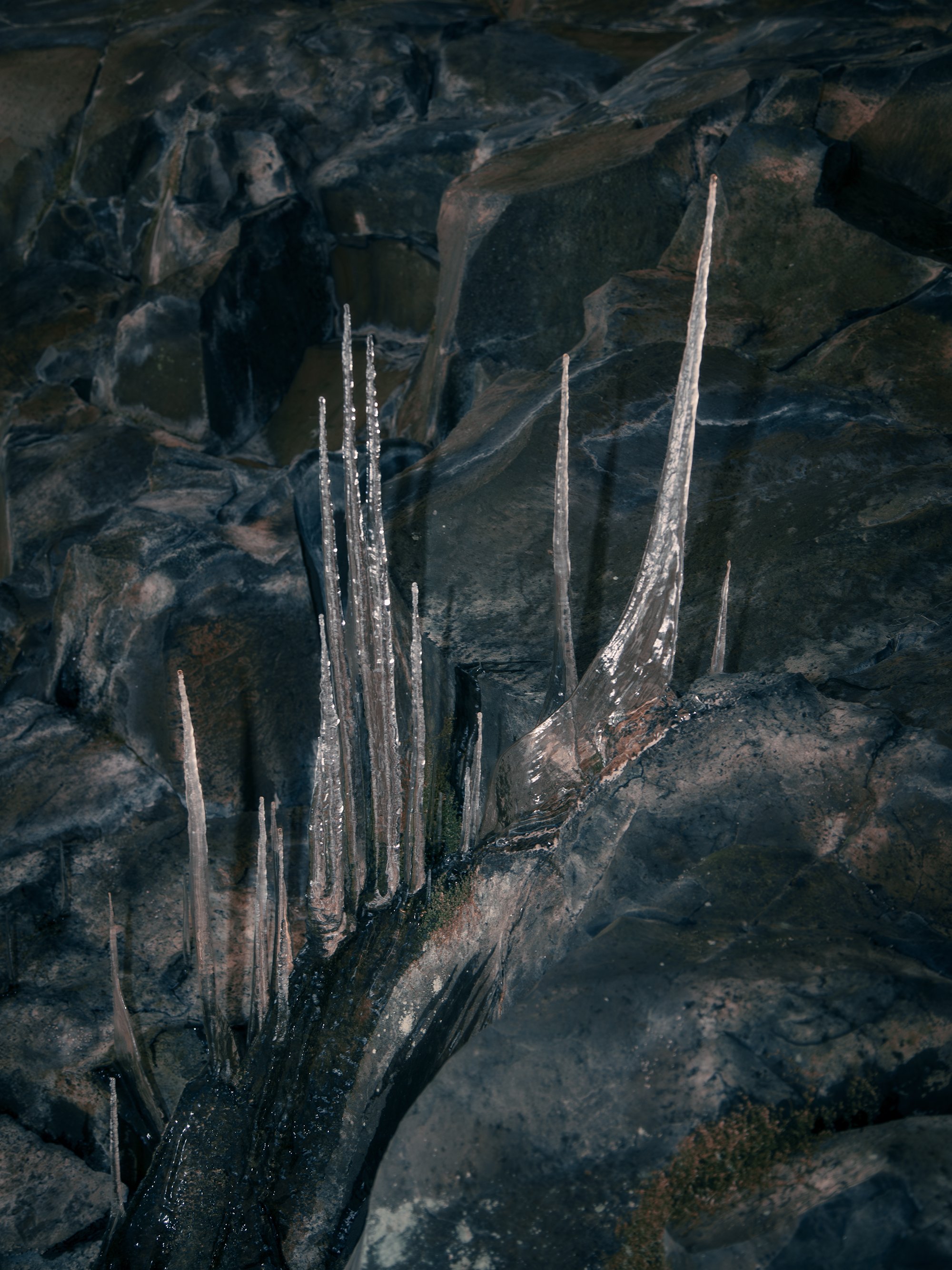 Close-up of jagged rocks with thin icicles hanging from them.