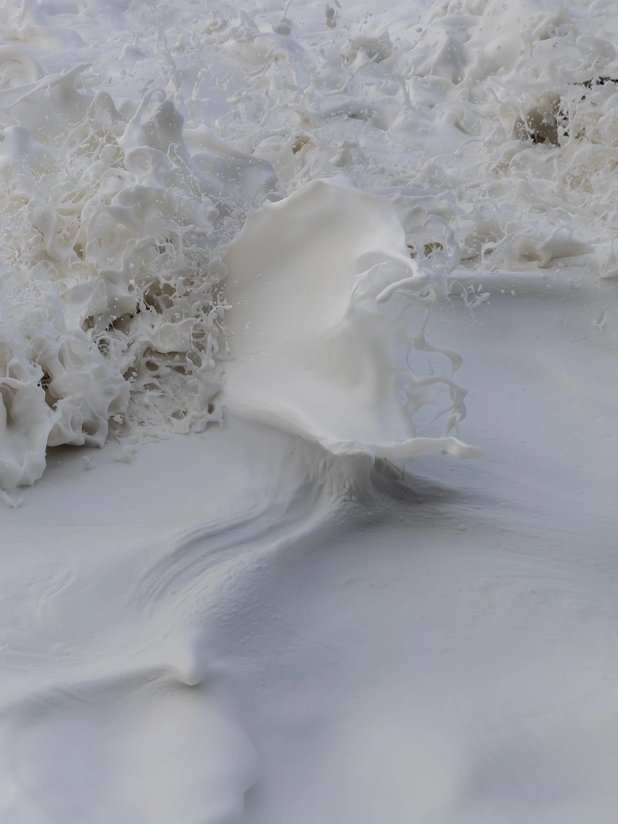 Close-up of white foam and splashing water, likely at the beach or in the ocean.